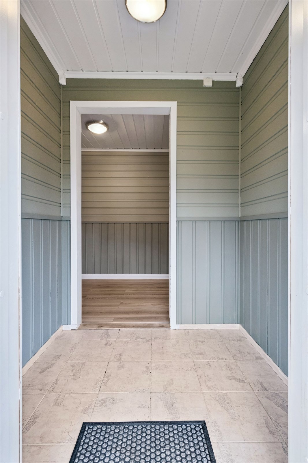 Her kommer du inn i en entré med lyse flier på gulvet og grønnmalt stående og liggende panel på veggene. Her kan du innredet med det du ønsker å ha i entréen. Videre inn kommer du til gangen. Galleribilde