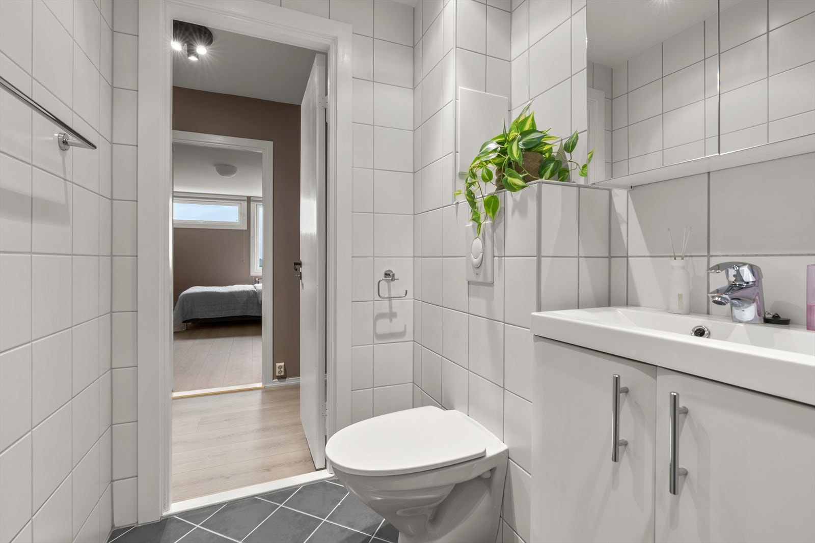 Badet er utstyrt med vegghengt toalett, dusjhjørne med innfellbar glassdører, samt baderomsinnredning med servant og speilskap. Det er opplegg for vaskemaskin. Galleribilde