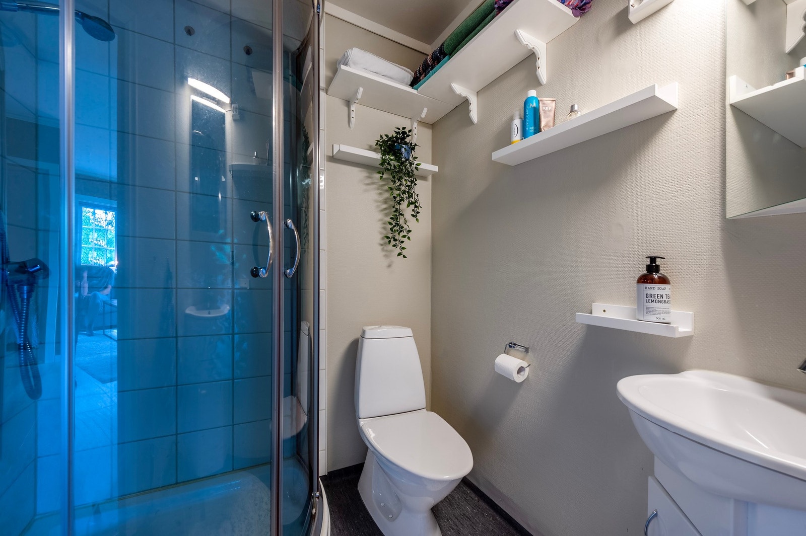 Badet er innredet med dusjhjørne, toalett og blant annet veggmontert servant. Galleribilde