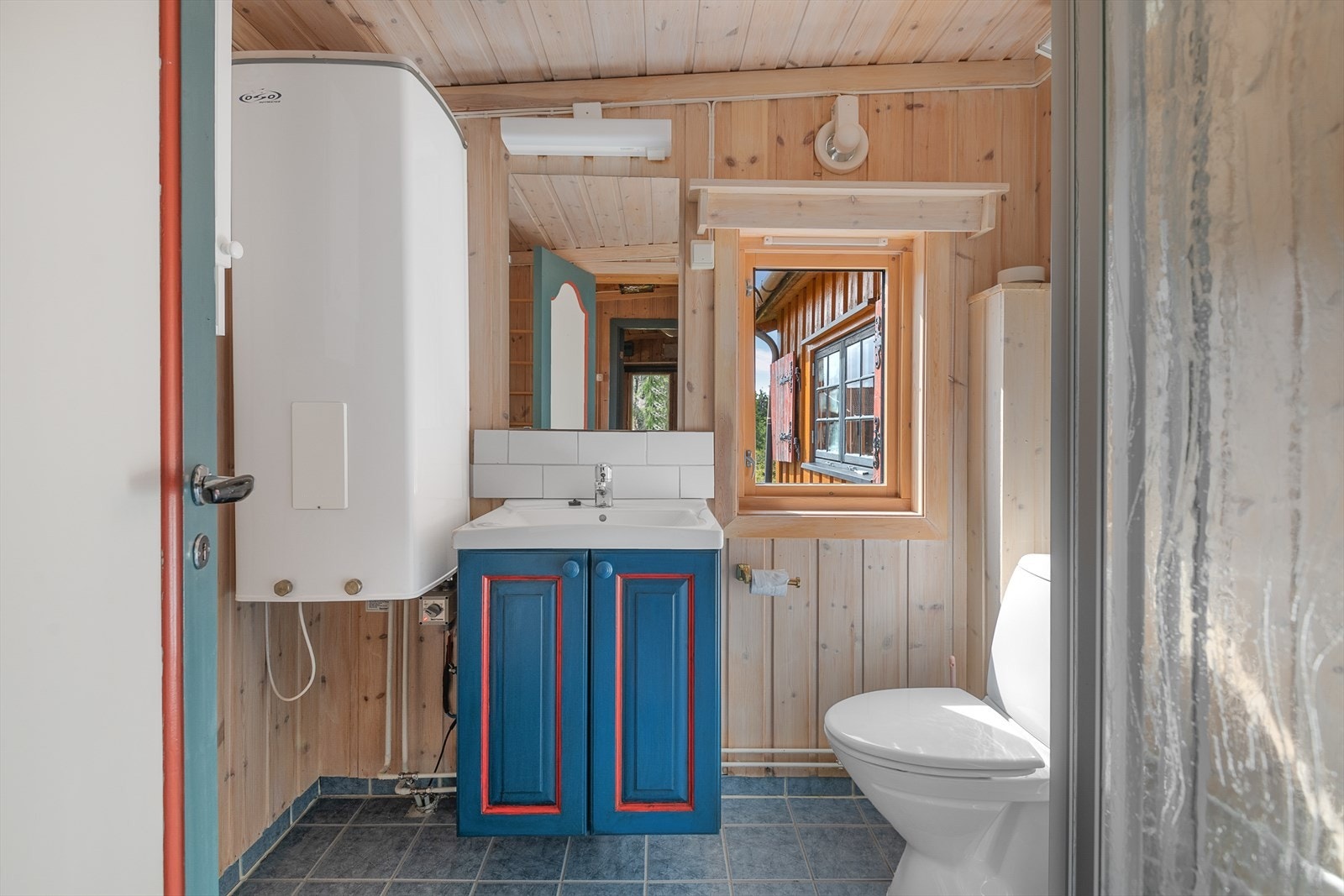 Funksjonelt bad/wc med servantinnredning og dusj. Varmtvannsbereder montert på vegg. Galleribilde