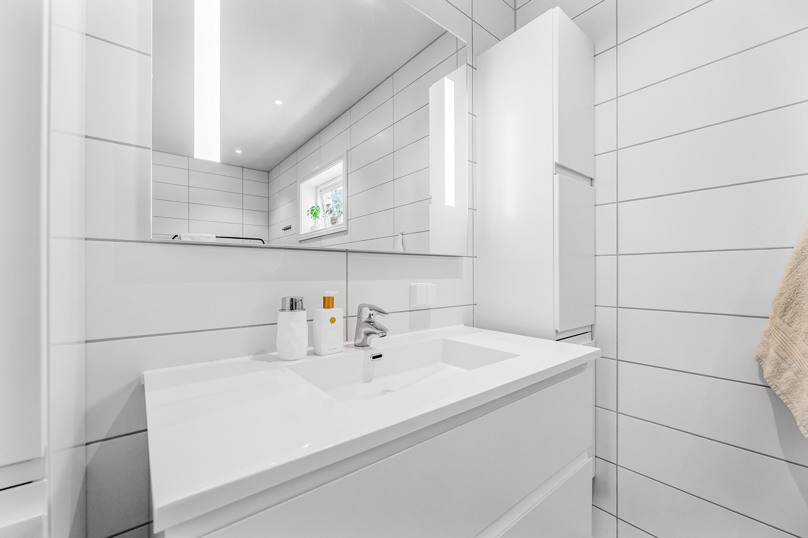 Benkeskap og veggskap med glatte fronter. Speil med belysning over servant. Galleribilde