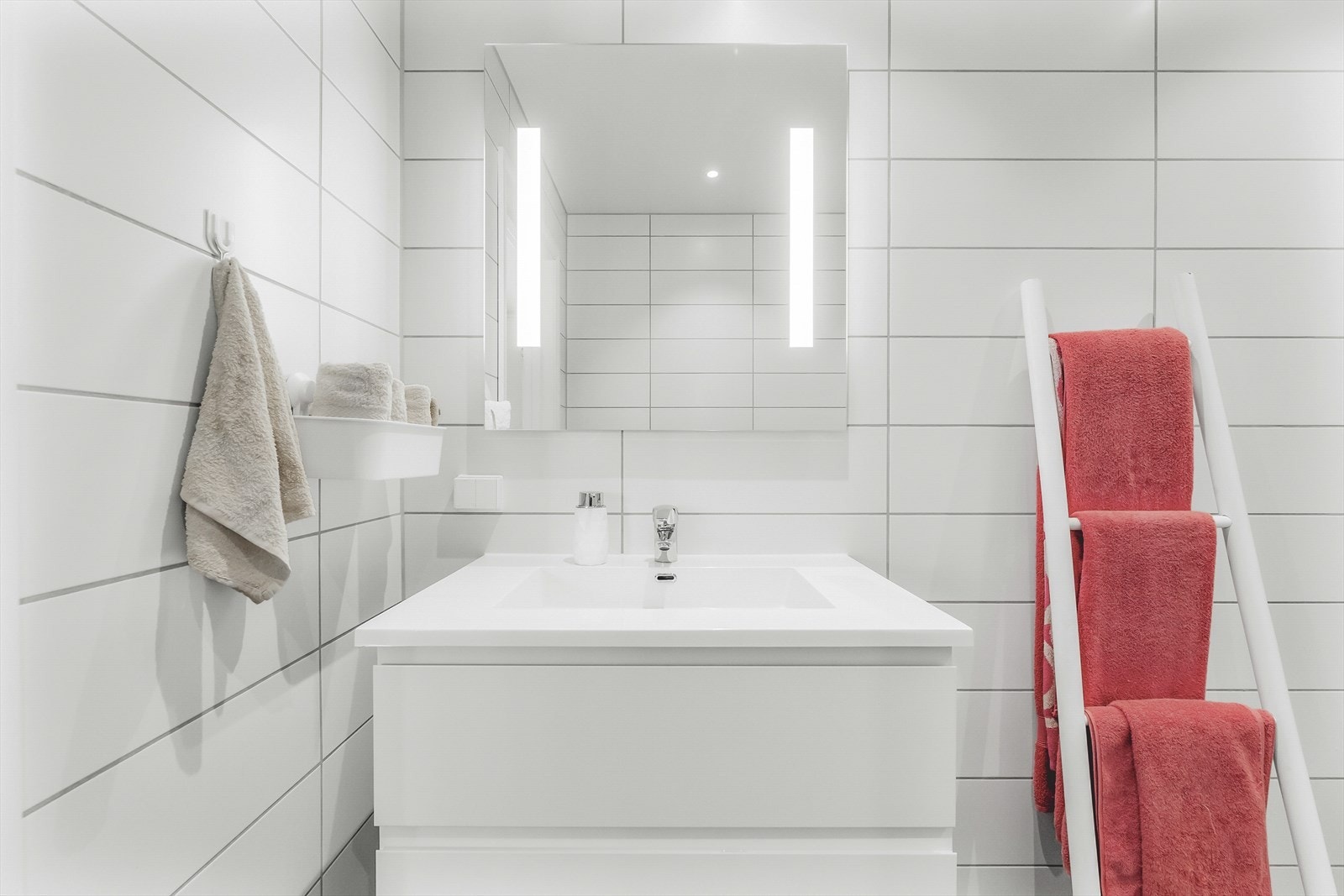 Benkeskap med glatte fronter og speil med belysning over servant. Galleribilde