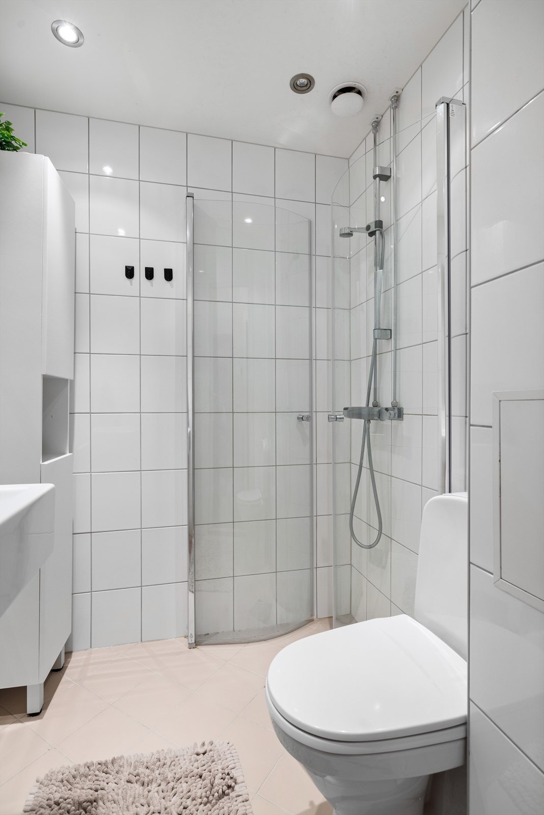 Badet er utstyrt med flislagte vegger/gulv og himling med nedfelte downlights. Innredning bestående av dusj, dusjdører i hedret glass, klosett, servant, speil og skap med oppbevaring Galleribilde