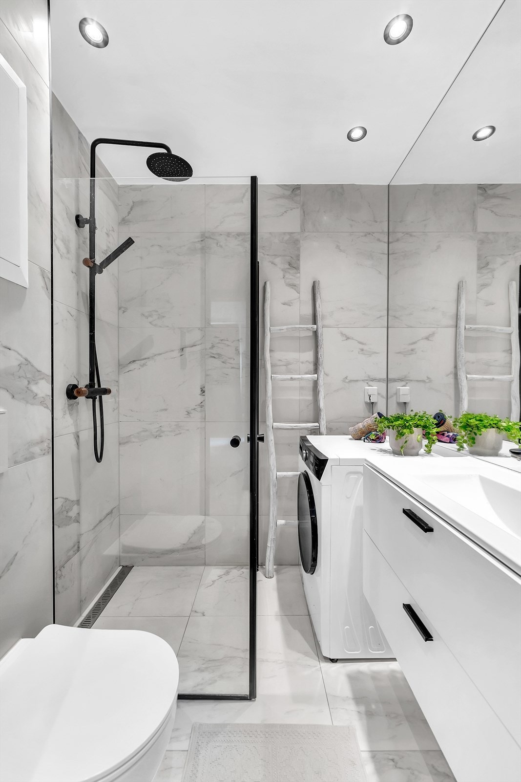 Badet har dusjhjørne med regnfallsdusj, vegghengt wc, servant med skuffer og opplegg for vaskemaskin. Galleribilde