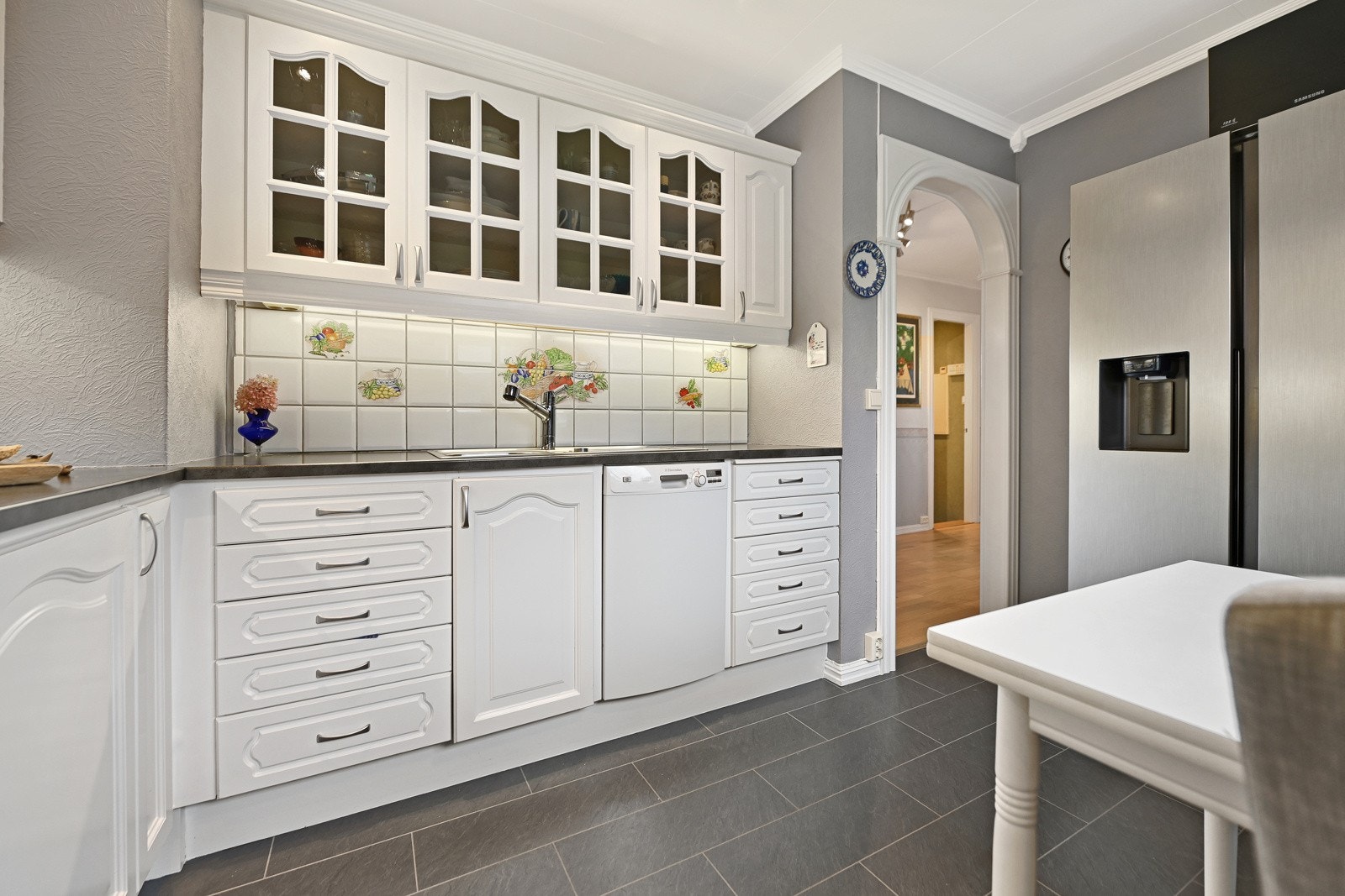 Innredningen er med profilerte fronter og laminat benkeplate. Frittstående komfyr og kjøl/fryseskap, underbygget oppvaskmaskin. Galleribilde