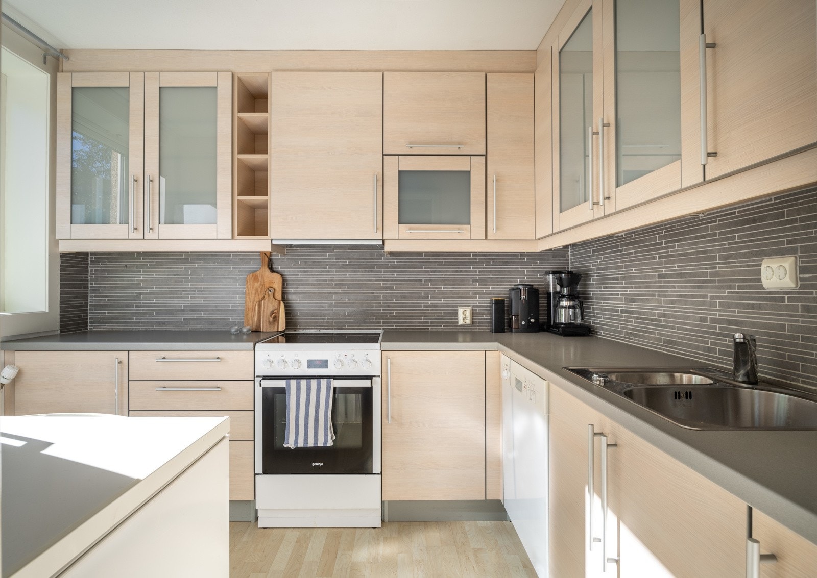 Romslig og lyst kjøkkeninnredning med slette fronter og benkeplater av laminat Galleribilde