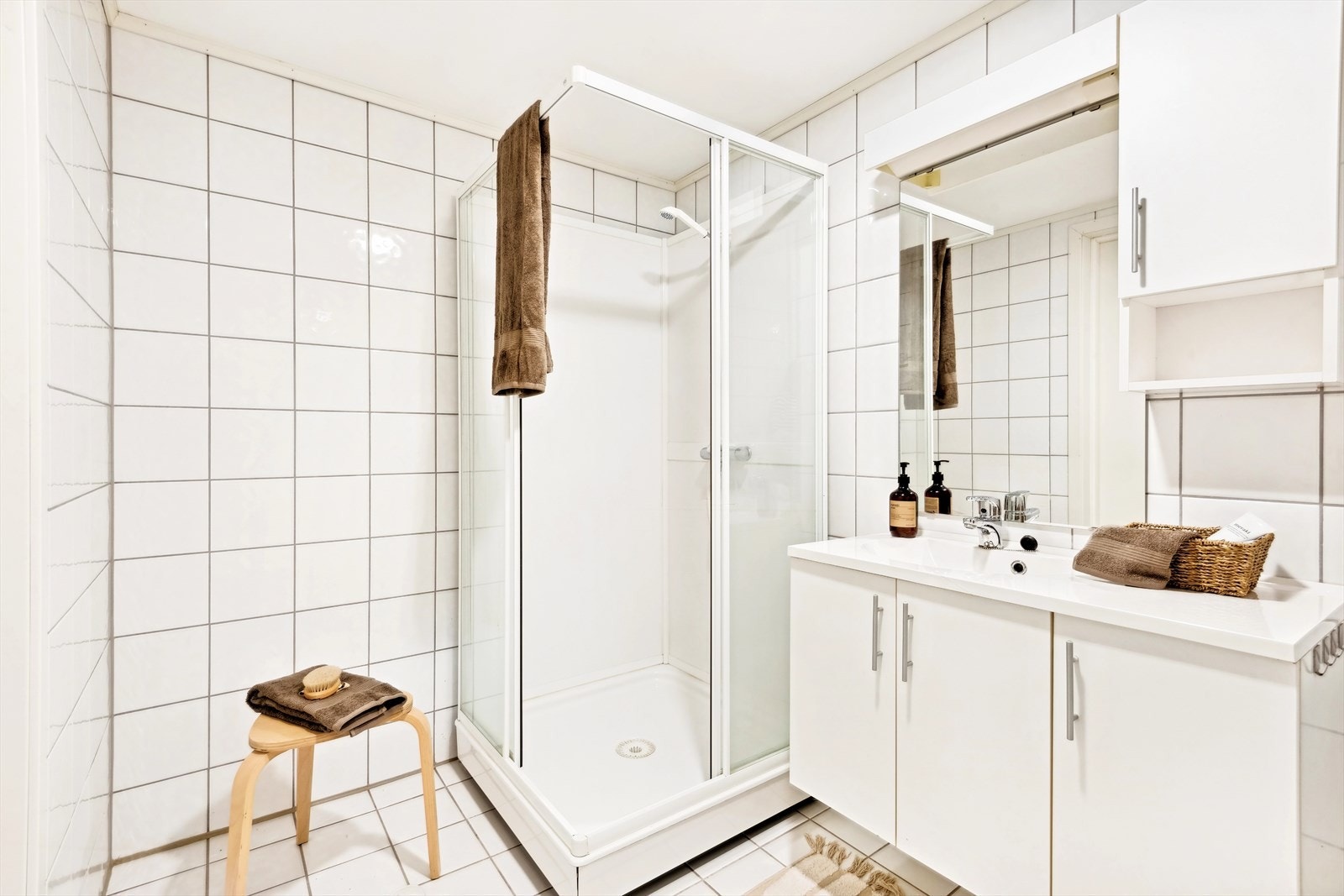 Flislagt baderom innredet med nedfelt servant, toalett og dusjkabinett. Det er opplegg for vaskemaskin. Galleribilde