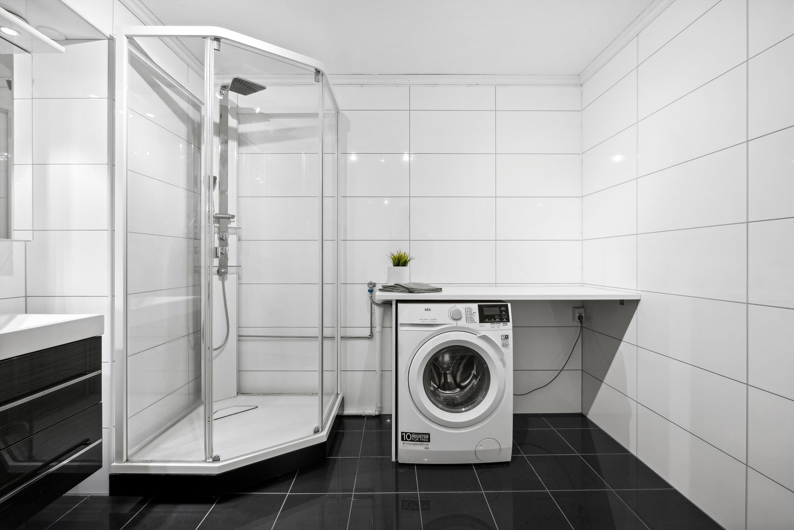 Badet er utstyrt med dusjkabinett, servant med skuffeseksjon, skapinnredning, samt opplegg for vaskemaskin. Galleribilde