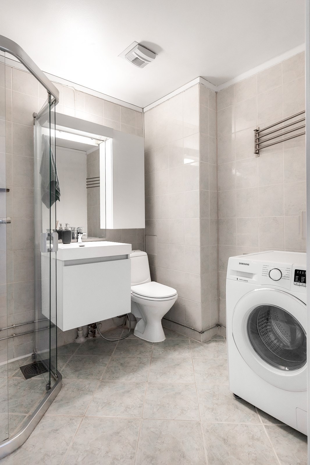 Videre har badet dusjhjørne med vegger/dør i herdet glass og toalett. Kombinert vaskemaskin/tørketrommel medfølger. Galleribilde
