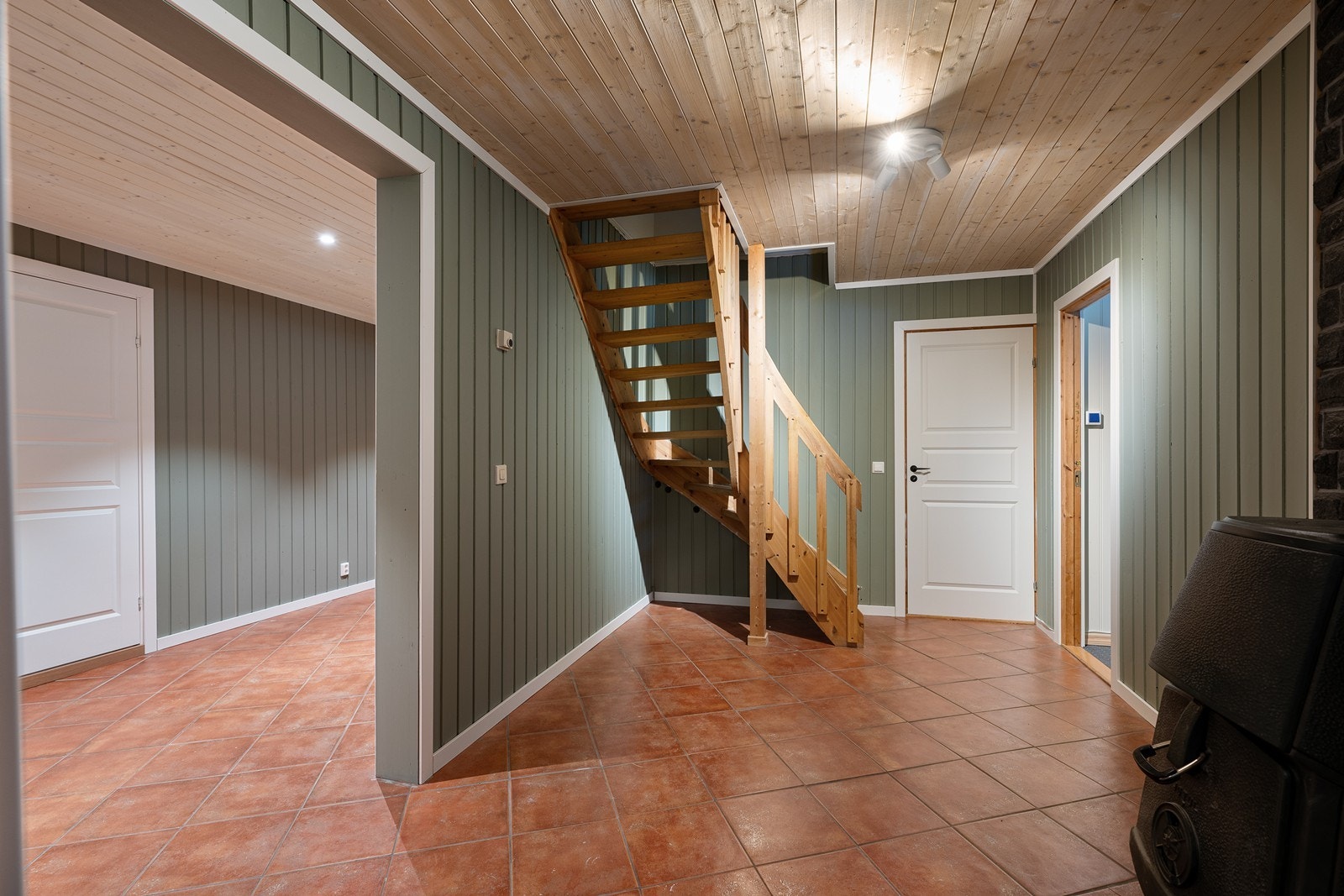 Trappegang i underetasjen med flislagt gulv, og Jøtul vedovn. Galleribilde