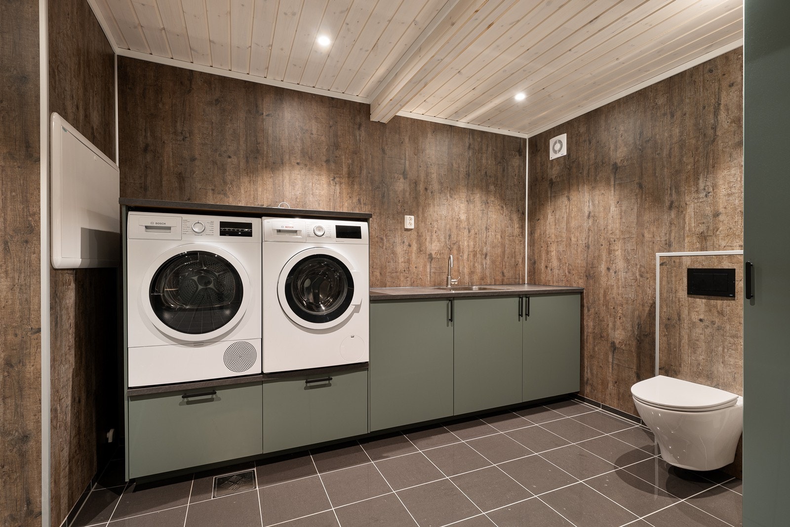 stilfull vaskeromsinnredning med grønne skap under en grå laminatbenkeplate med kum i stål. Galleribilde