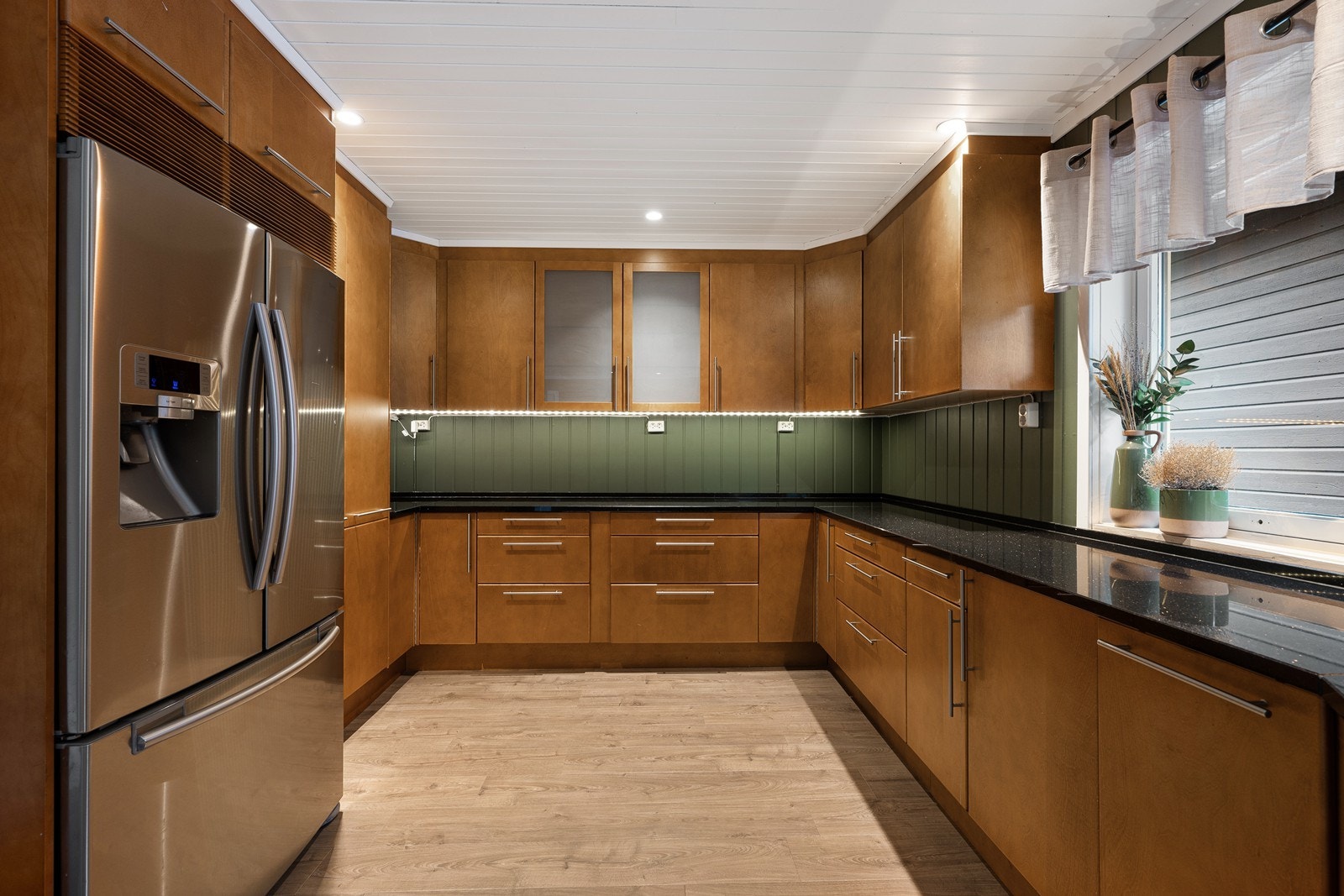 Kjøkkeninnredningen har glatt, gylne fronter, takhøye skap og sort benkeplate i stein. Galleribilde