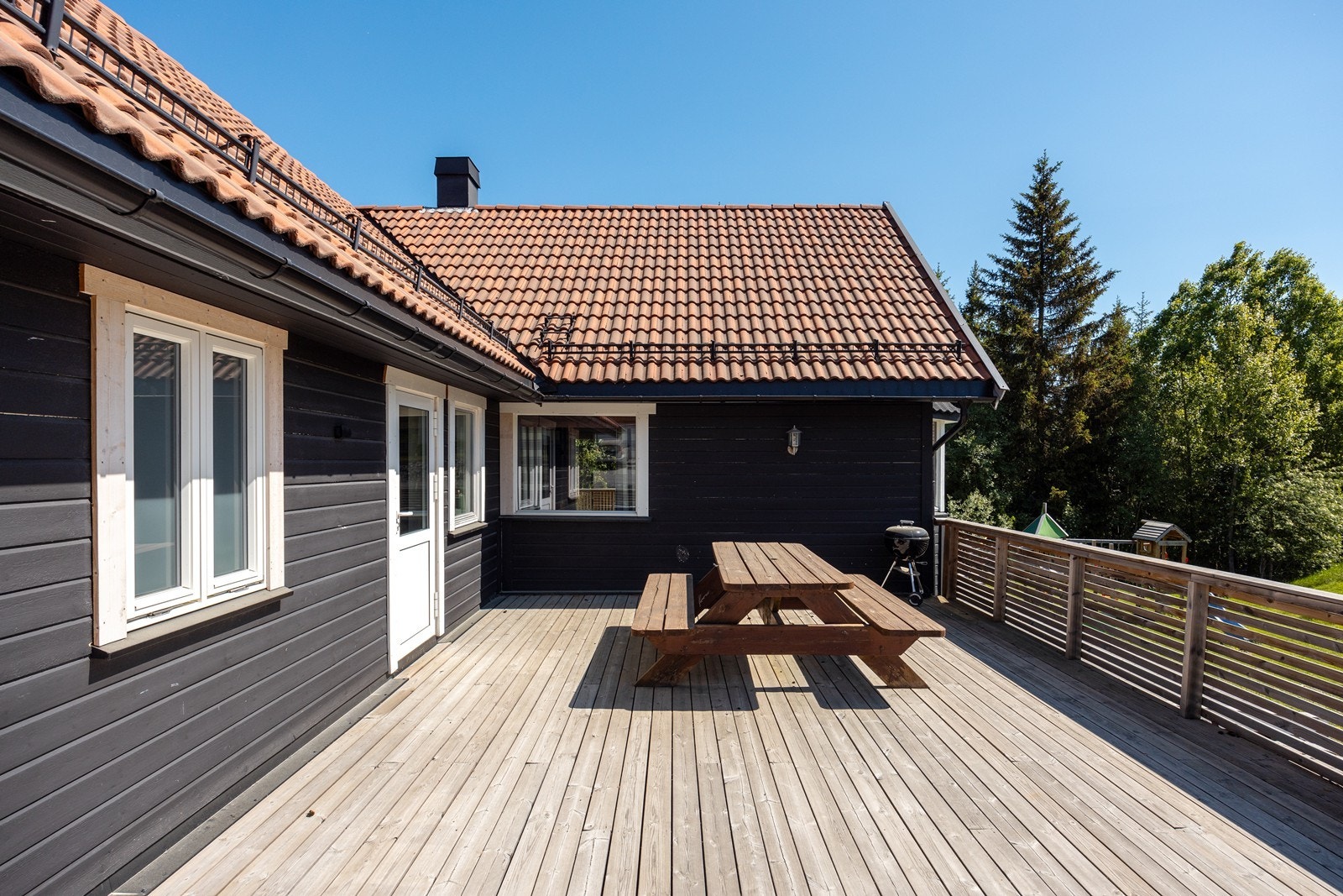 Det er flere fine uteplass med terrasse rundt tre sider av huset. Dette er en romslig terrasse med adkomst fra kjøkkenet. Terrassen har trapp til hagen. Galleribilde