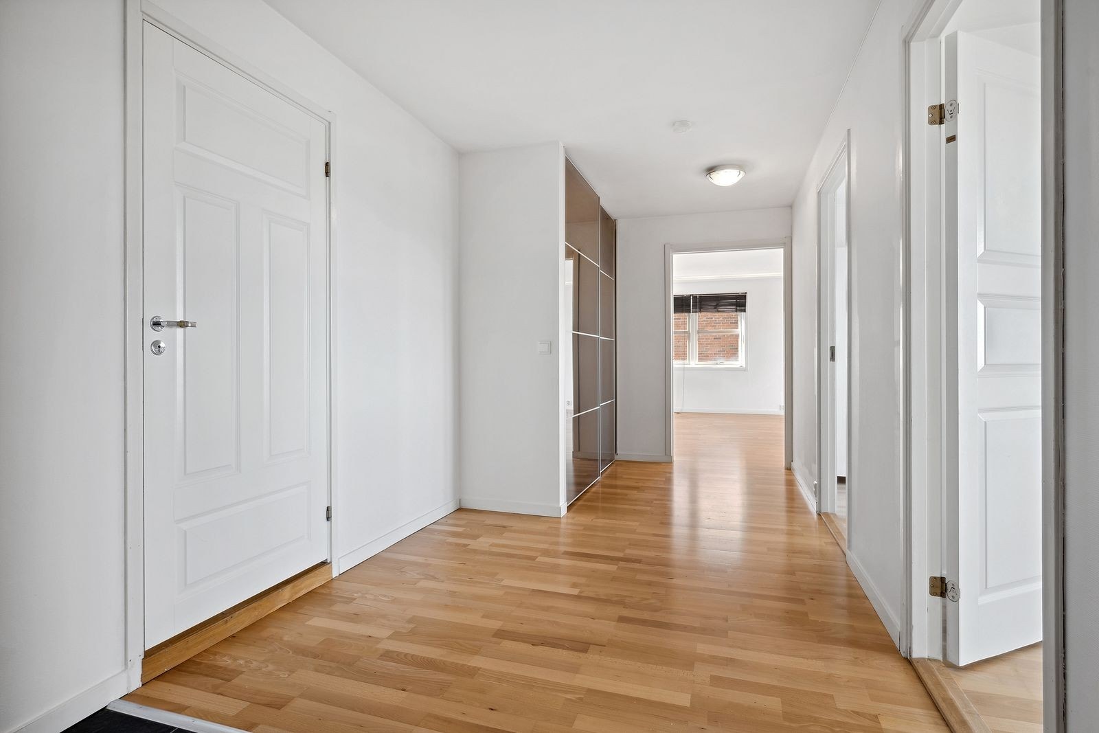 Luftig gang/ hall med stor skyvedørsgarderobe. Galleribilde