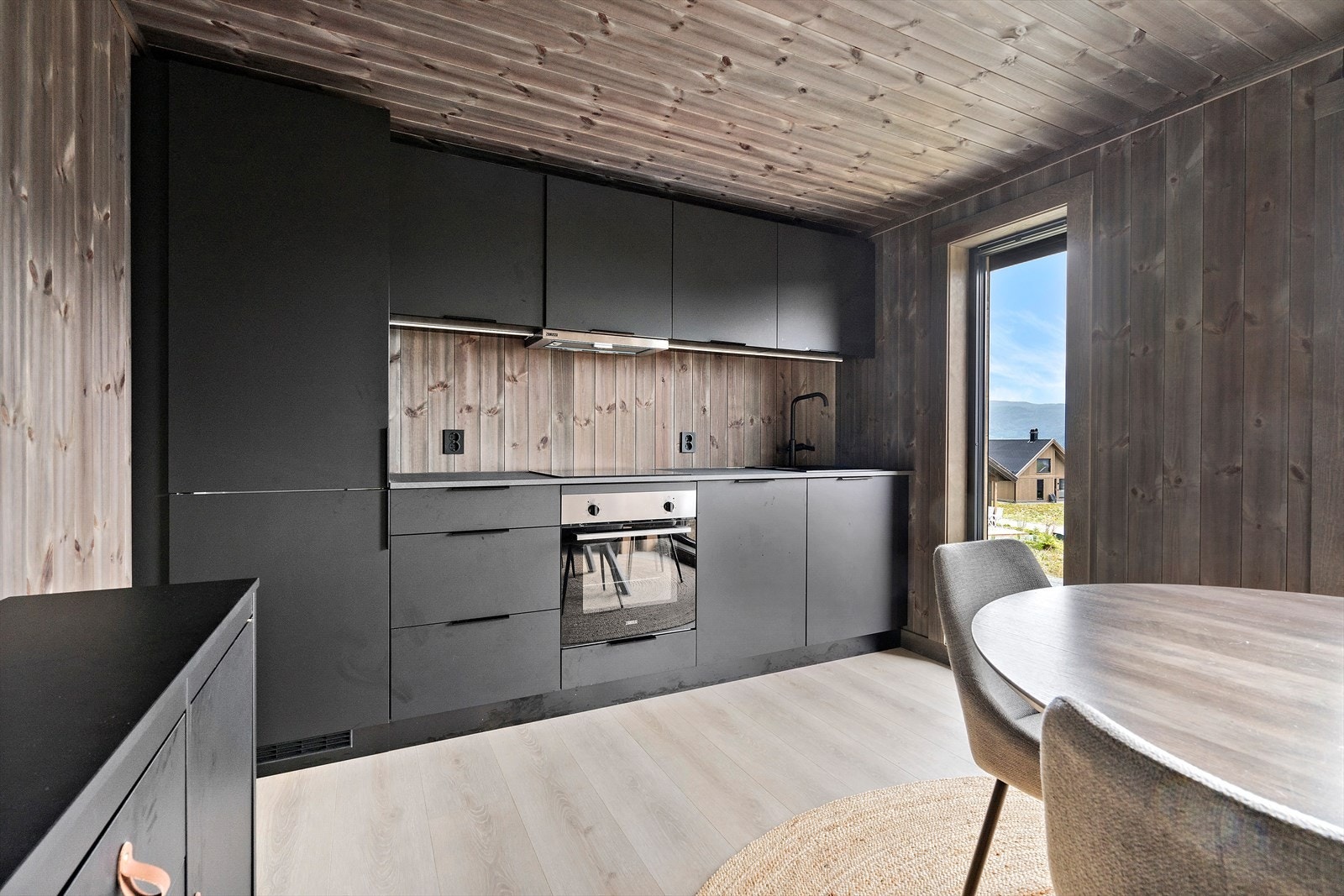 Stilrent kjøkken med mørke og slette overflater. De integrerte hvitevarene medfølger. Galleribilde