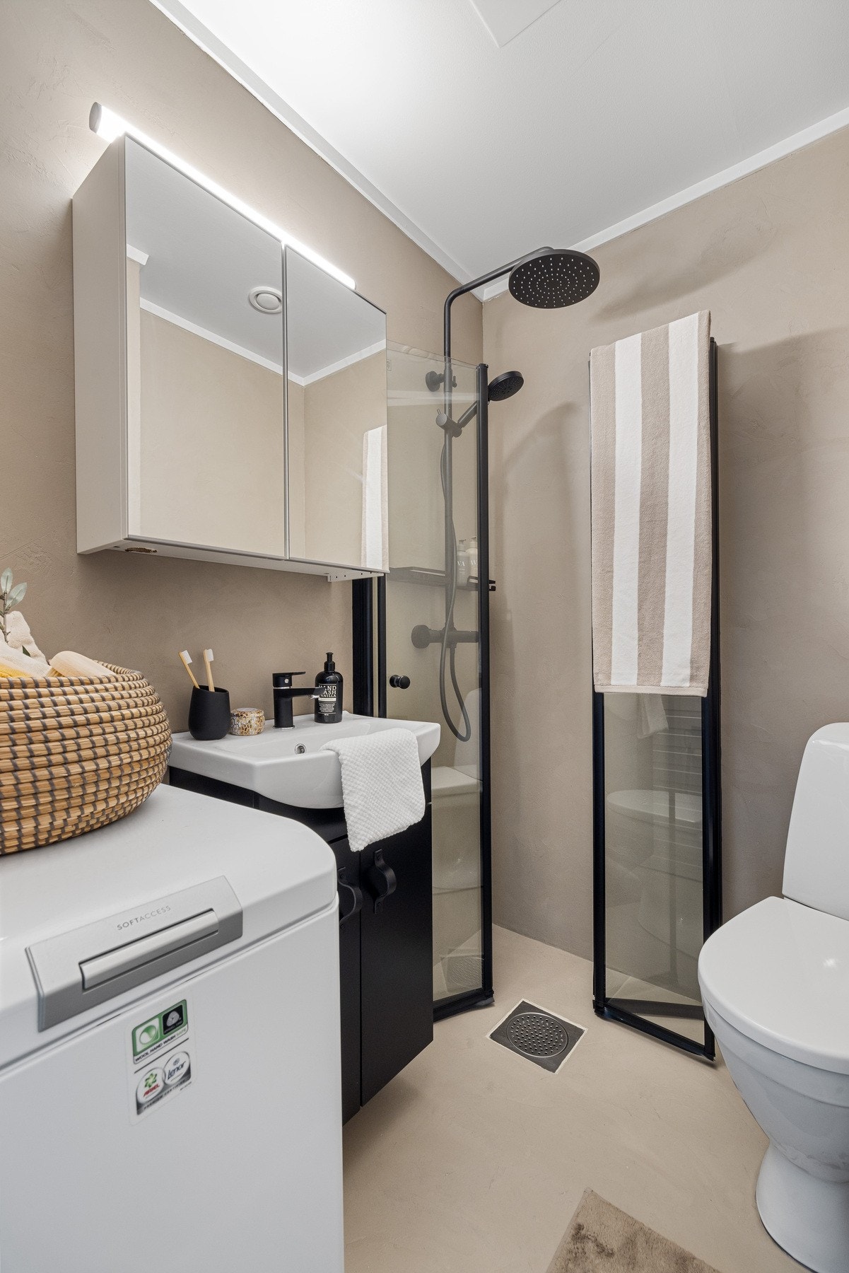 Badet har høyskap, speil, servantskap, dusj med glassdører og opplegg for vaskemaskin/tørketrommel. Galleribilde