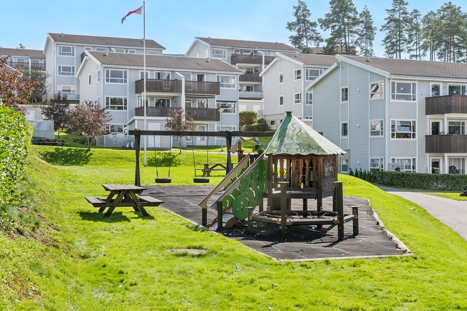Borettslaget har store gressområder, grillplass og en liten lekeplass med klatrestativ, lekestue og flere husker. Galleribilde