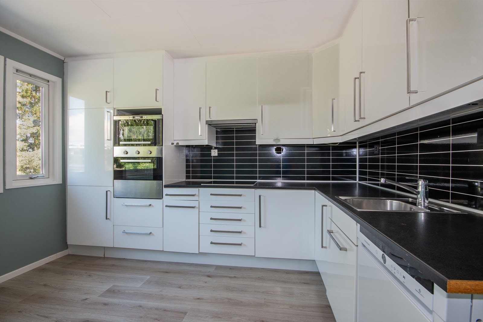 IKEA kjøkken med hvite høyglansfronter, takhøye overskap og integrerte hvitevarer. Galleribilde