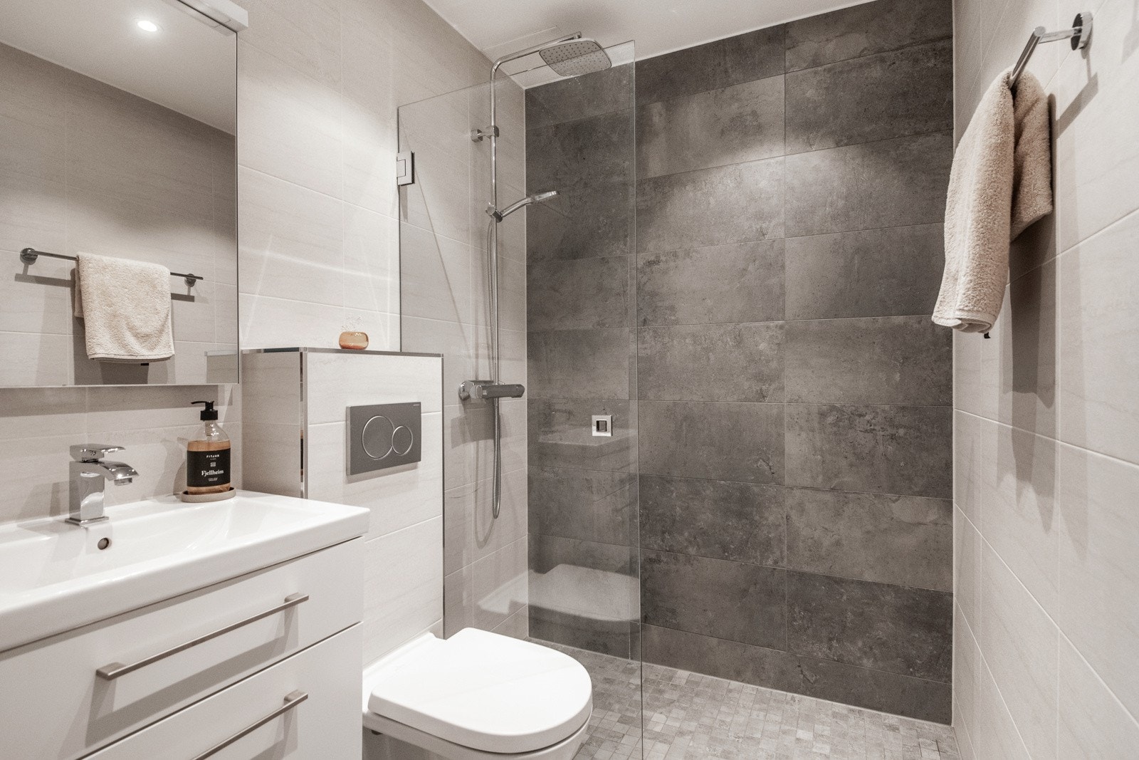 Romslig baderom med moderne flis- og materialvalg. Godt med oppbevaring i servantskap. Galleribilde