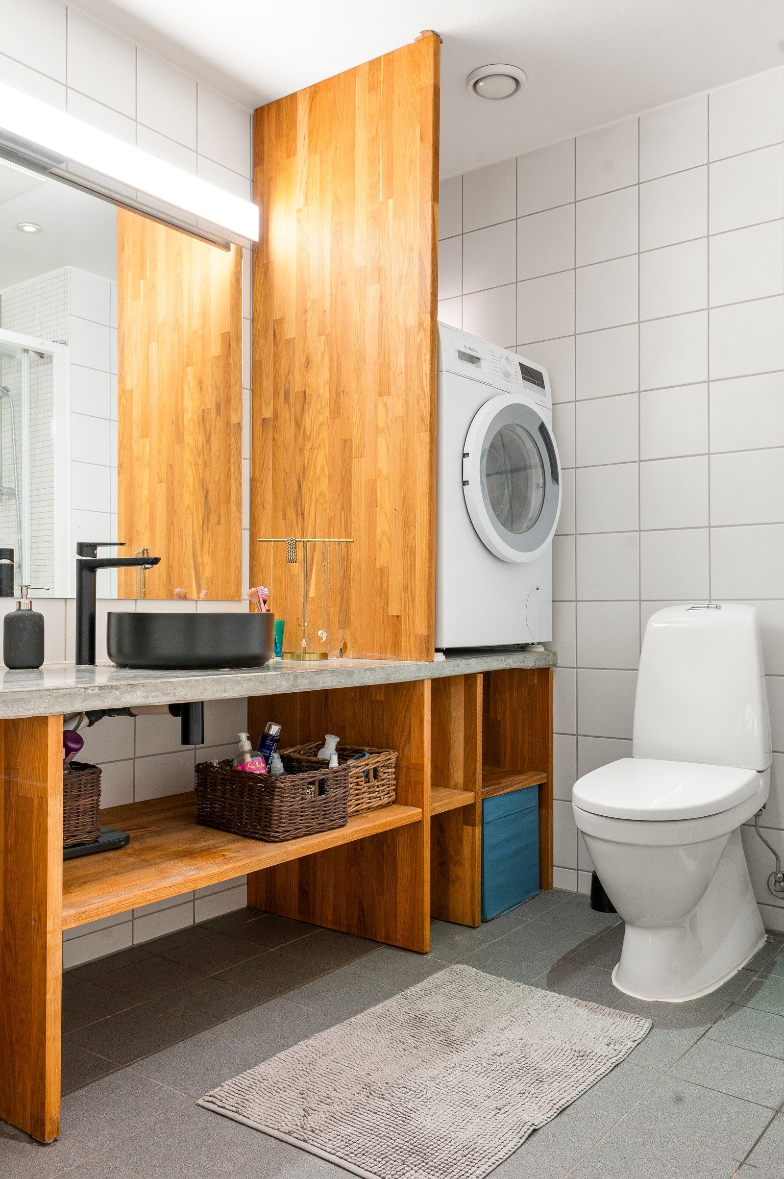 Bred innredning fra 2021 med eikehyller, heldekkende betongplate og ovenpåliggende servant. Galleribilde