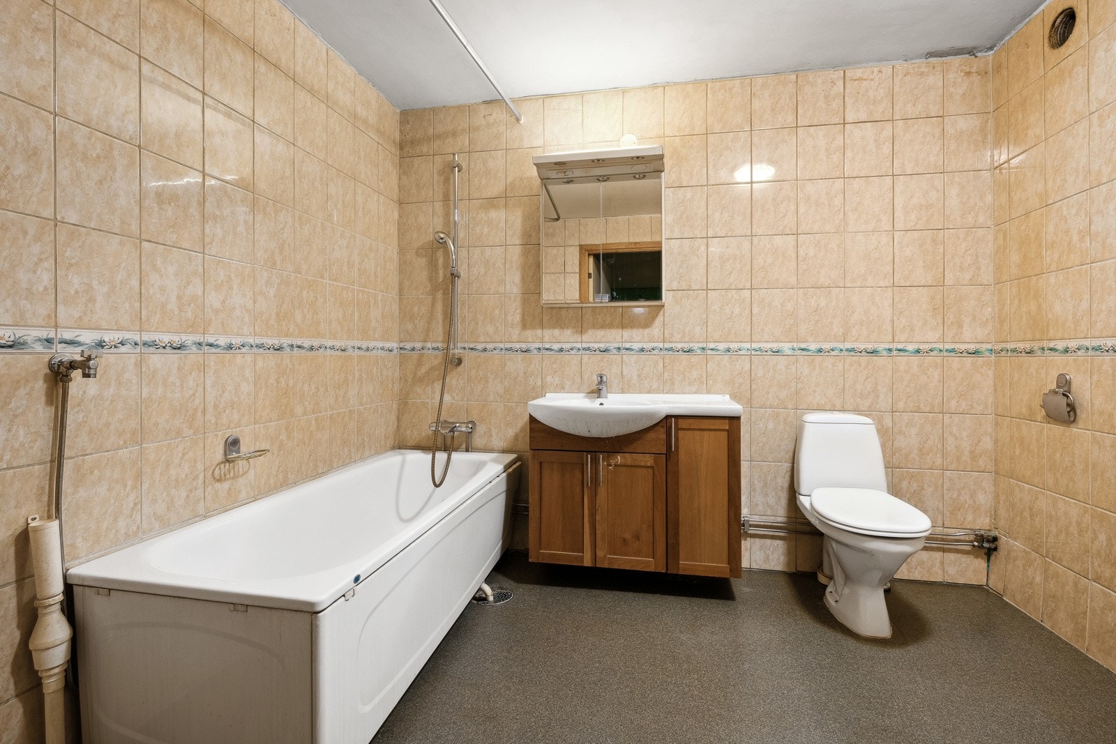 Eldre flislagt bad belegg på gulv og flislagte vegger. Badet har opplegg for vaskemaskin. Galleribilde