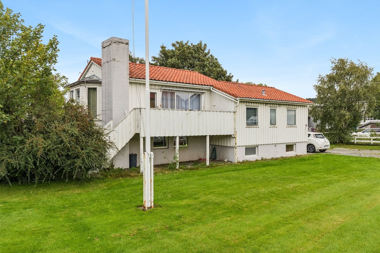 Stor, solrik eiendom som er opparbeidet med plen, busker og gruset gårdsrom. Galleribilde