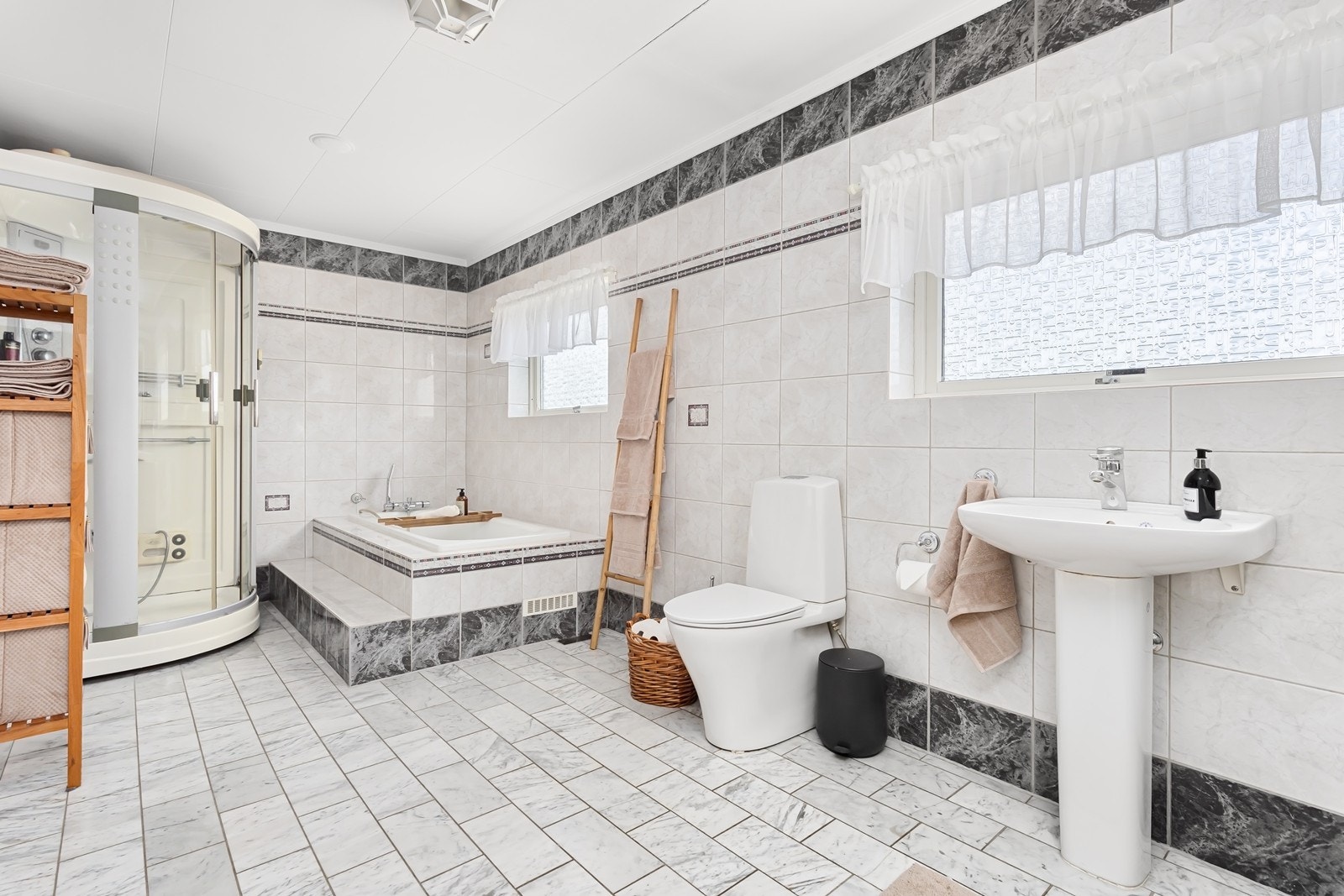 Badet i 2.etasje har marmor fliser med varmekabler i gulv. Badet er romslig og utstyrt med inn fliset badekar, dusjkabinett med ulike funksjoner og toalett. Galleribilde