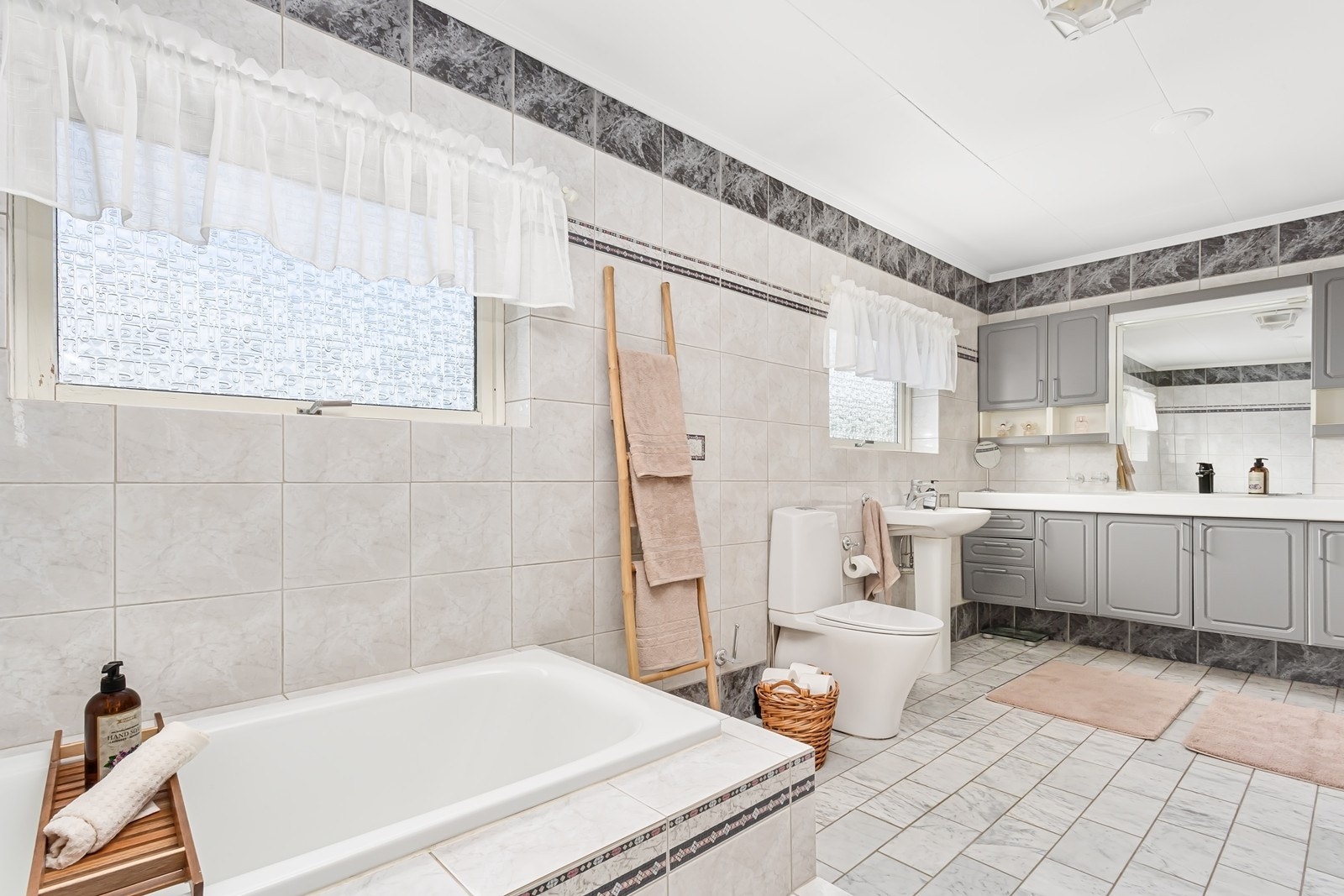 Klassisk grå servantinnredning med god plass til oppbevaring i skap, heldekkende nedfelt servant og speil med belysning. Galleribilde