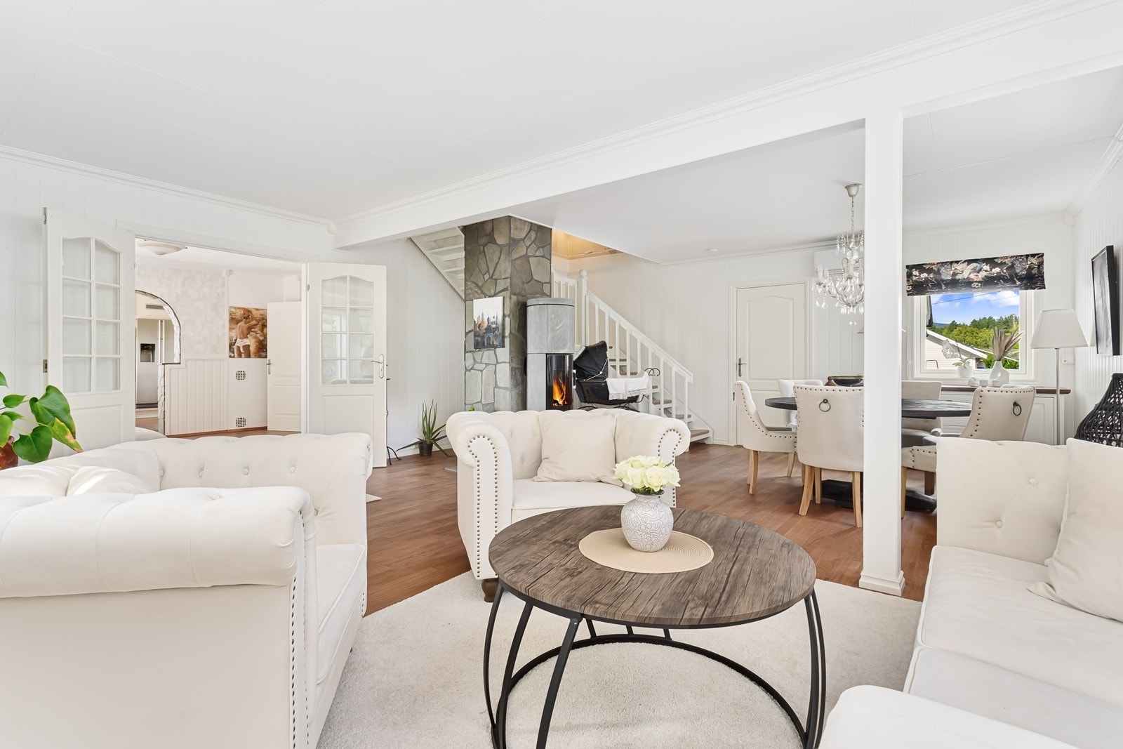 Stuen fremstår som lekker og delikat med parkett på gulv og malt panel på vegg i et lyst fargepalett. Galleribilde