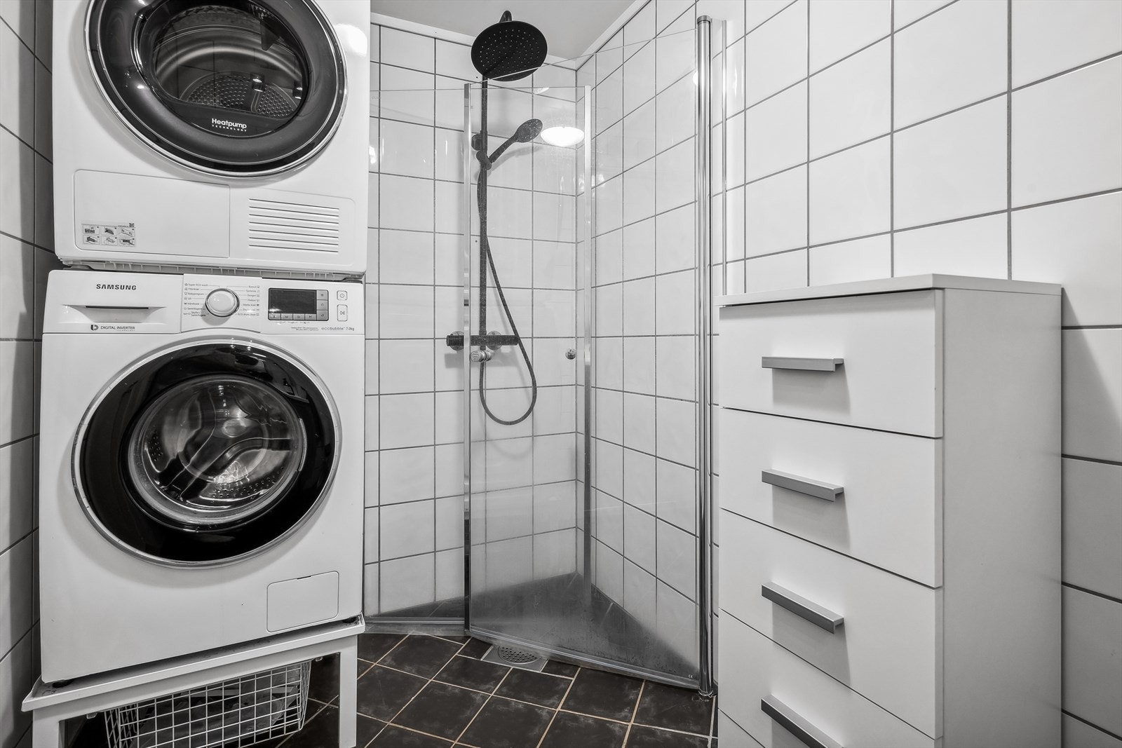 Badet er innredet med speil, servant med oppbevaring, toalett, dusjhjørne og opplegg for vaskemaskin. Galleribilde
