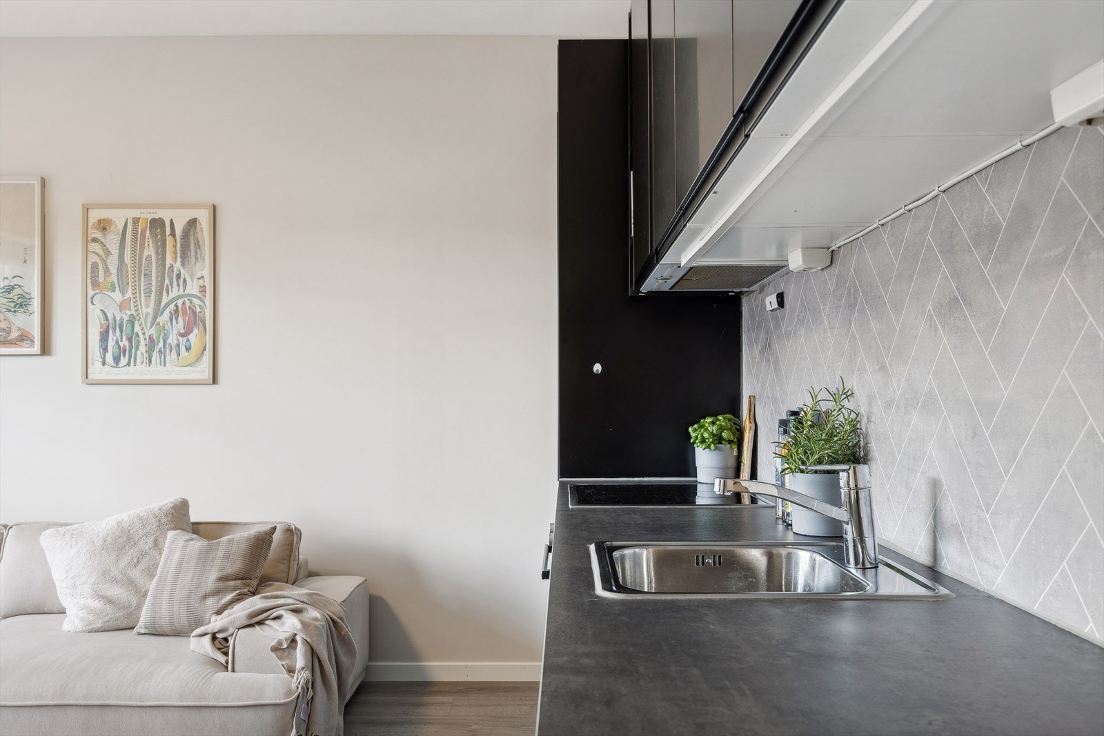 Benkeplaten er laget av laminat og har en nedfelt oppvaskkum. Mellom benkeplaten og overskapet er det montert moderne plater som gir et stilrent uttrykk. Galleribilde