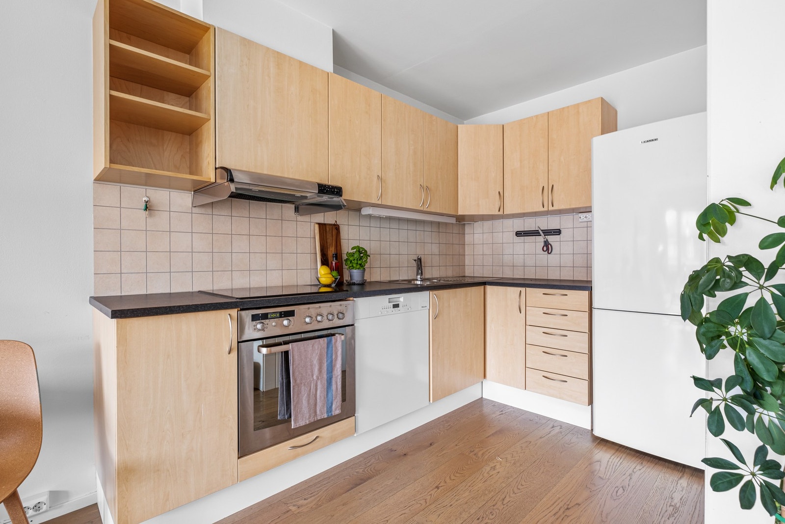 Pent kjøkken med integrerte platetopp, oppvaskmaskin og stekeovn. Galleribilde