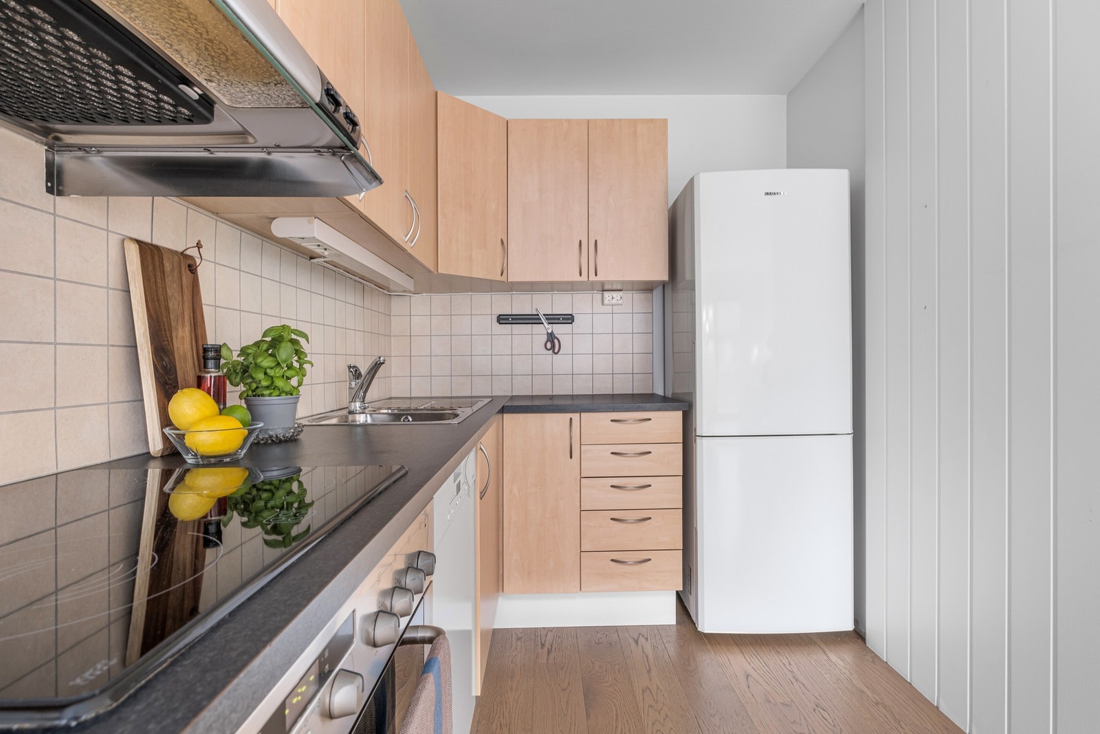 Pent kjøkken med integrerte platetopp, oppvaskmaskin og stekeovn. Galleribilde