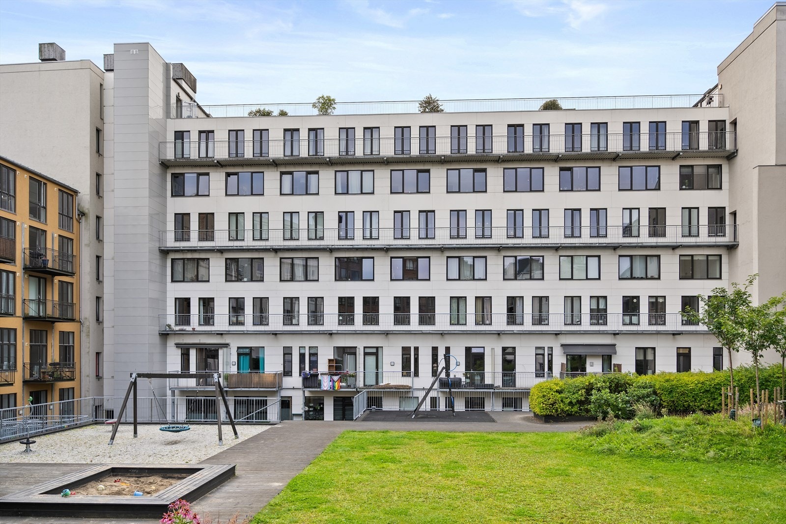 Pent opparbeidet og barnevennlig gårdsrom med huske, sandkasse og sittegrupper. Galleribilde