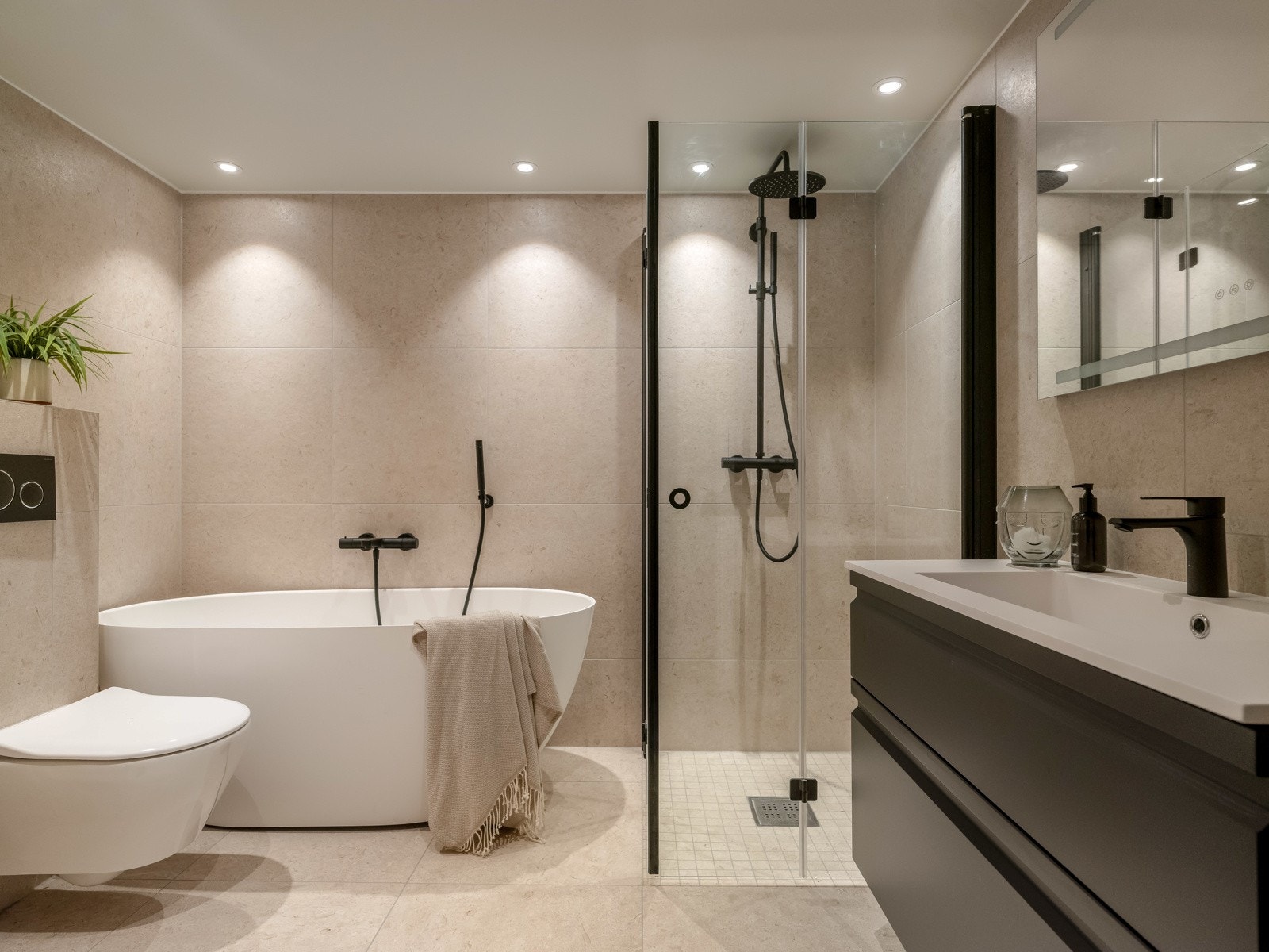 Det største badet er innredet med lekre fliser på gulv i kombinasjon med like fliser på vegger. Baderomsinnredningen består av skap, speil level 80x100 og sort servantkran. Galleribilde