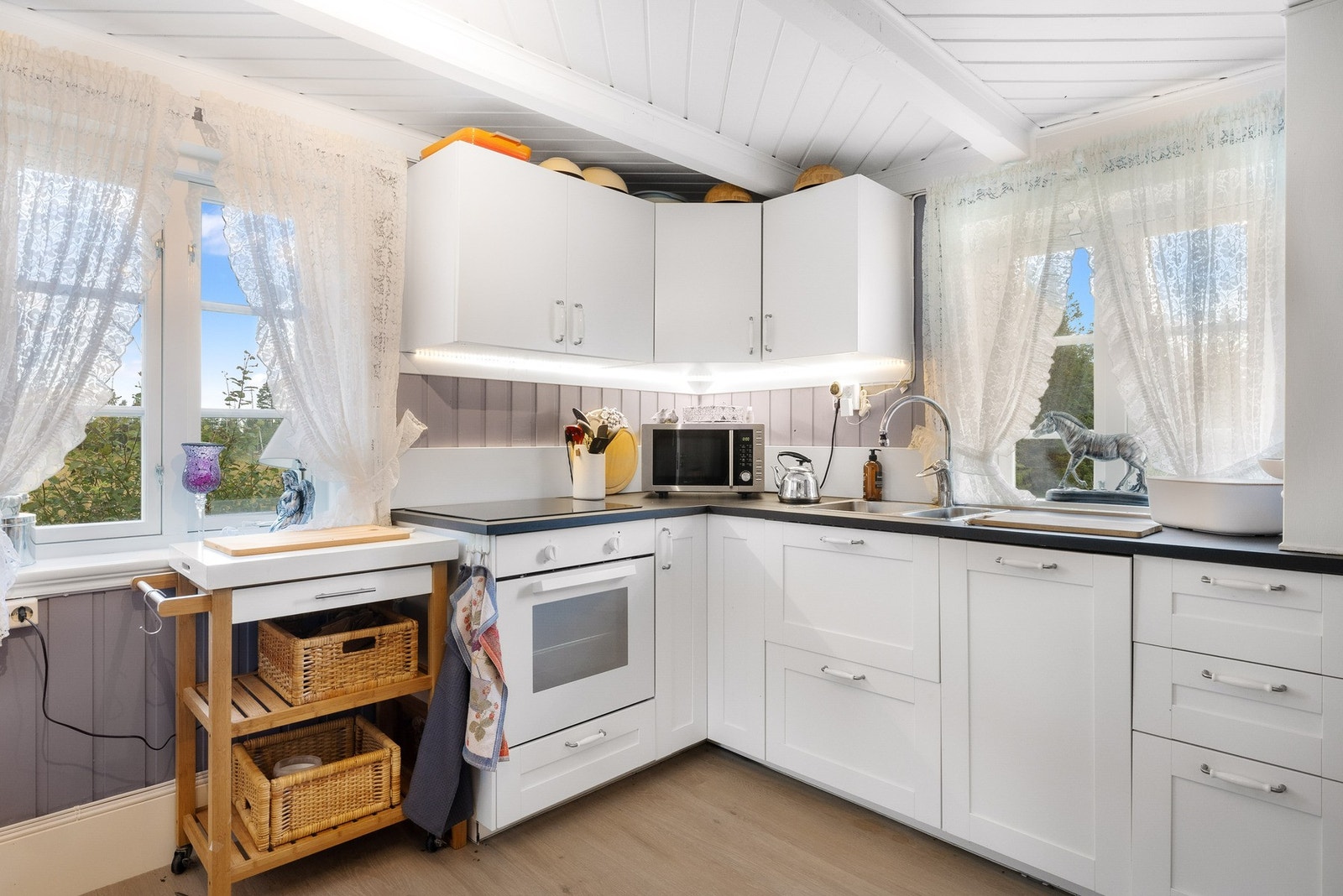 Kjøkkeninnredning med hvite fronter og mørk laminert benkeplate. Galleribilde