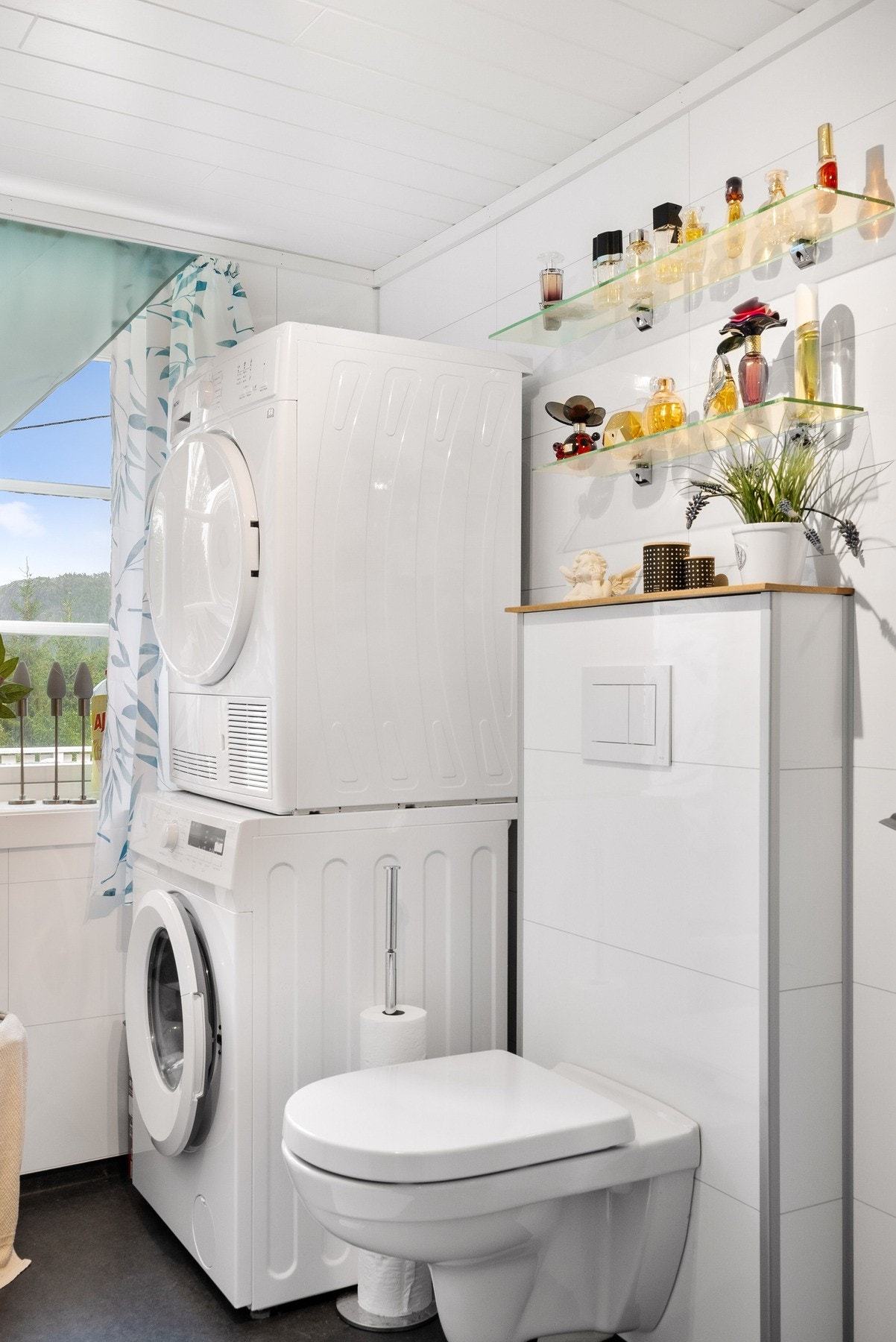 Badet er utstyrt med vegghengt toalett, baderomsinnredning, opplegg for vaskemaskin og dusj med innfellbare dusjvegger av glass. Galleribilde