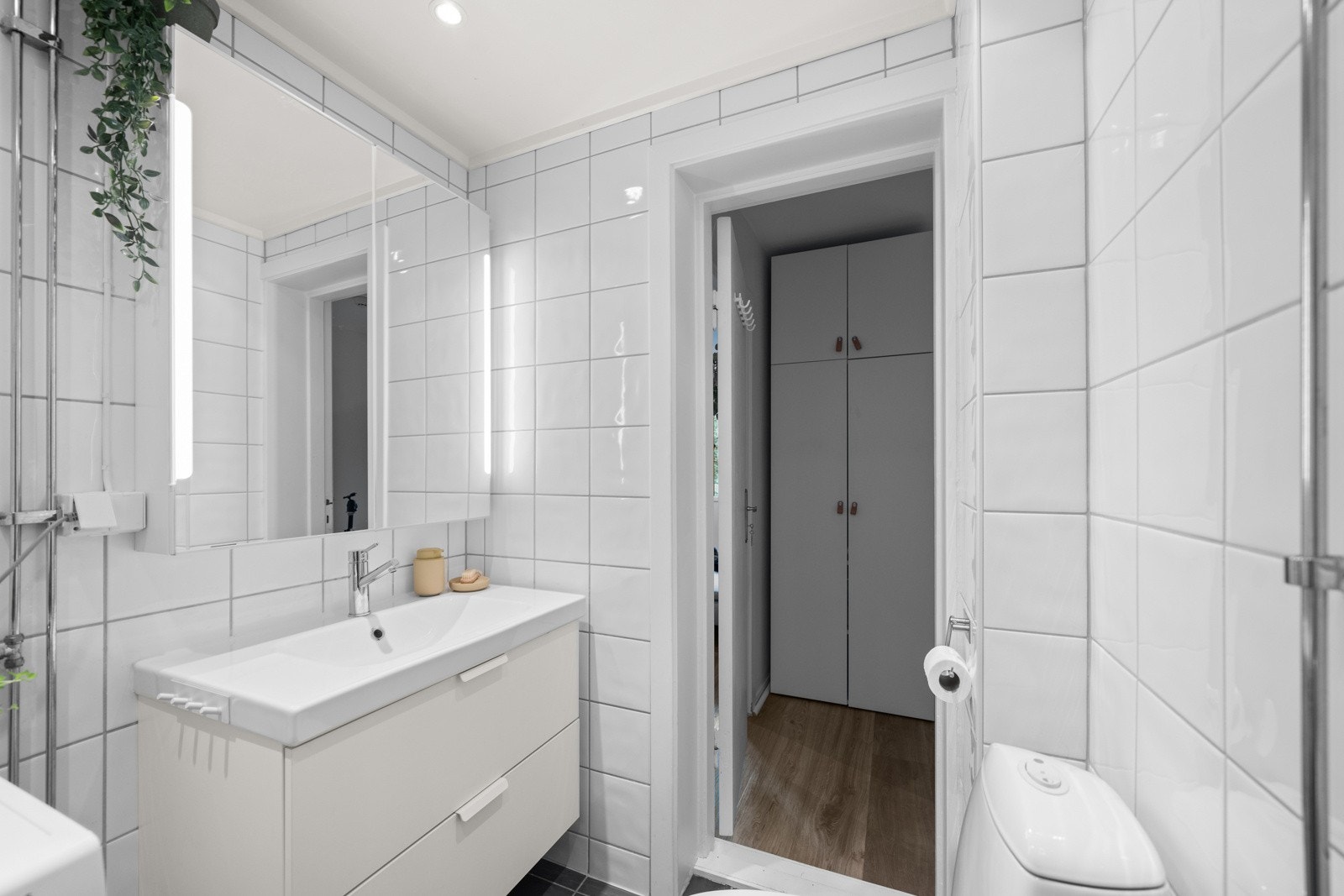 Badet er utstyrt med et dusjhjørne med glassdører, nedsenket servant med skap og speil, samt gulvmontert toalett. I tillegg er det opplegg for vaskemaskin og tørketrommel. Galleribilde
