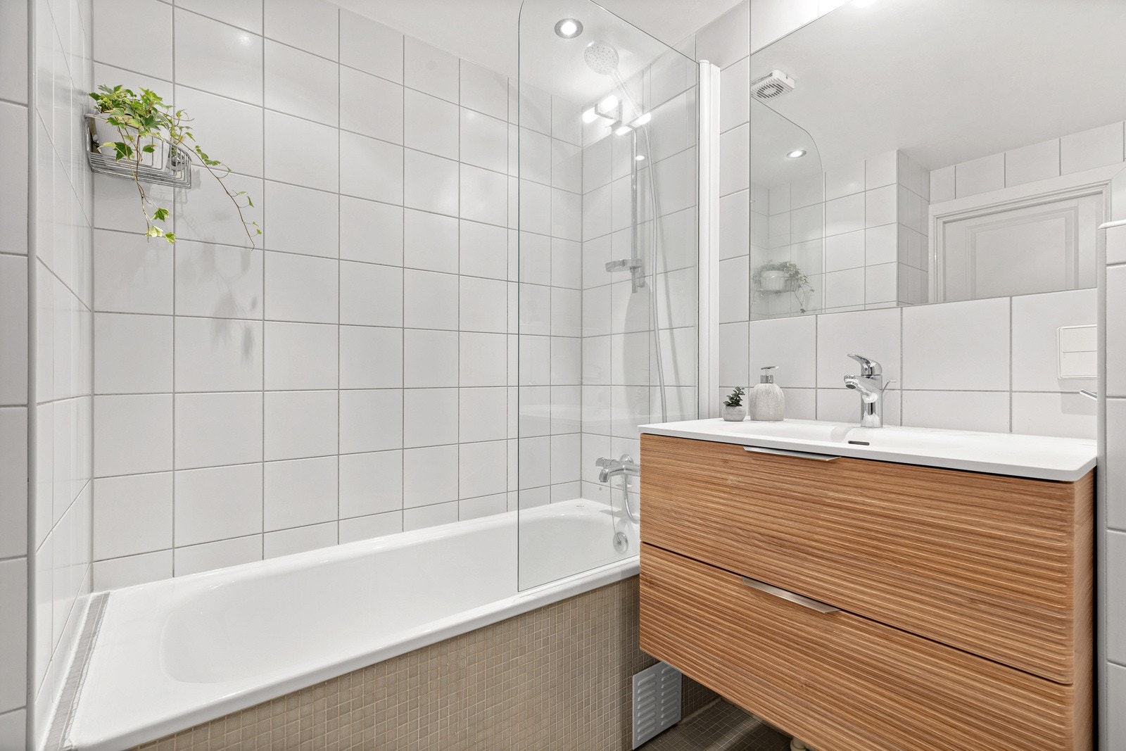 Badet er innredet med badekar, vegghengt toalett og servant med skuffer i underskap Galleribilde