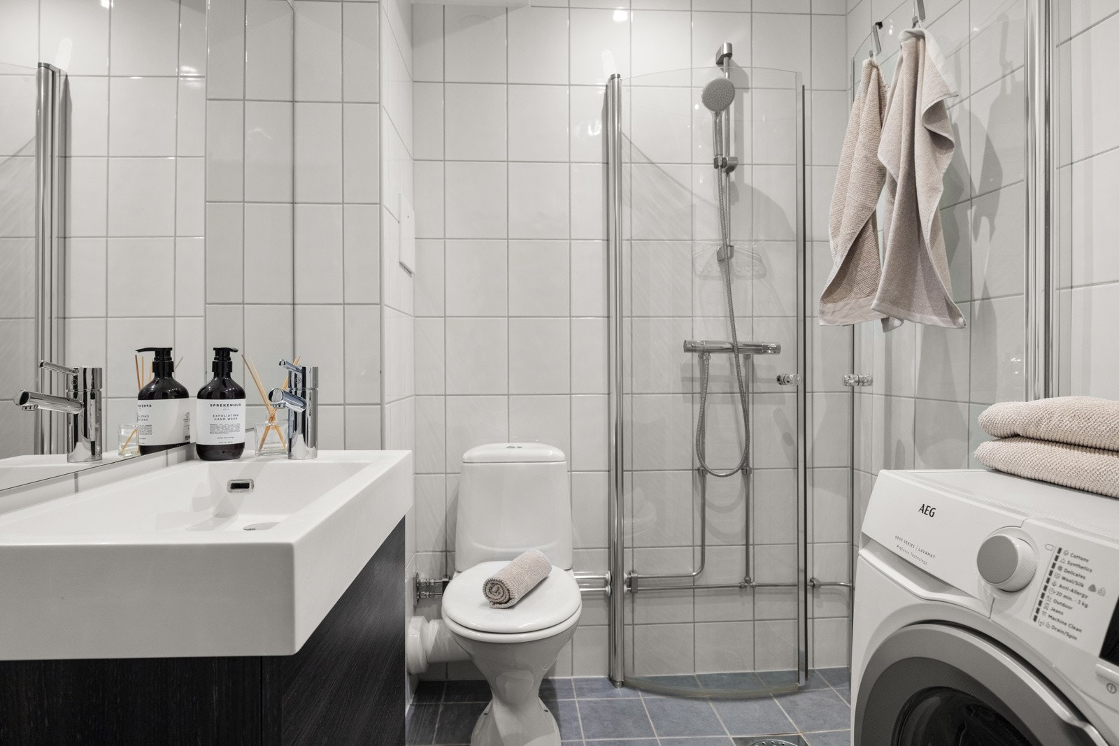 Delikat, flislagt bad med opplegg for vaskemaskin. Galleribilde