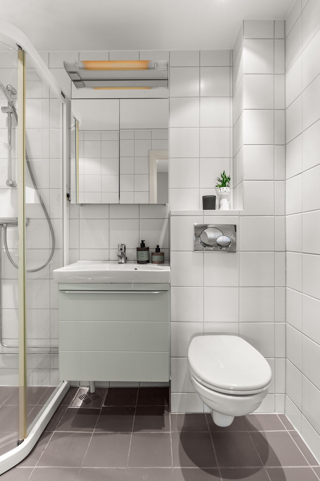 Videre har badet dusjhjørne med skyvbare dører i glass og vegghengt klosett. Det er opplegg for vaskemaskin. Galleribilde