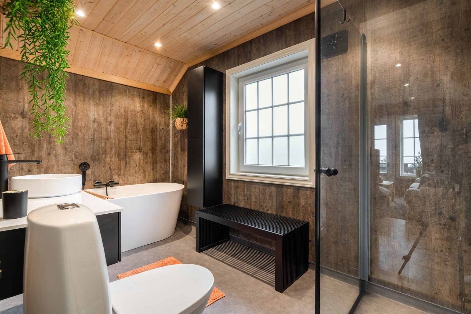 Stort og romslig baderom fra 2023 med overflater bestående av baderomsplater på vegger, vinylbelegg på gulv med elektriske varmekabler og panel i himling. Galleribilde