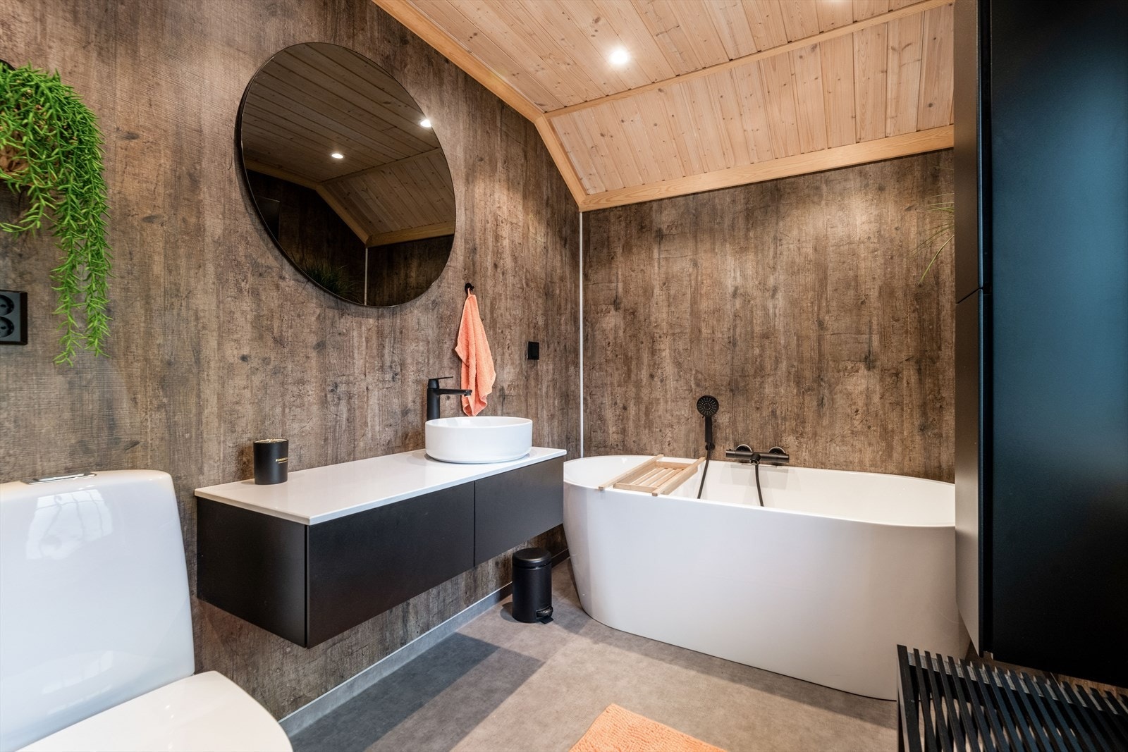 Flott slett innredning i sort med skuffer og benkeplate med frittstående servant. Over innredningen er det speilflate. Galleribilde