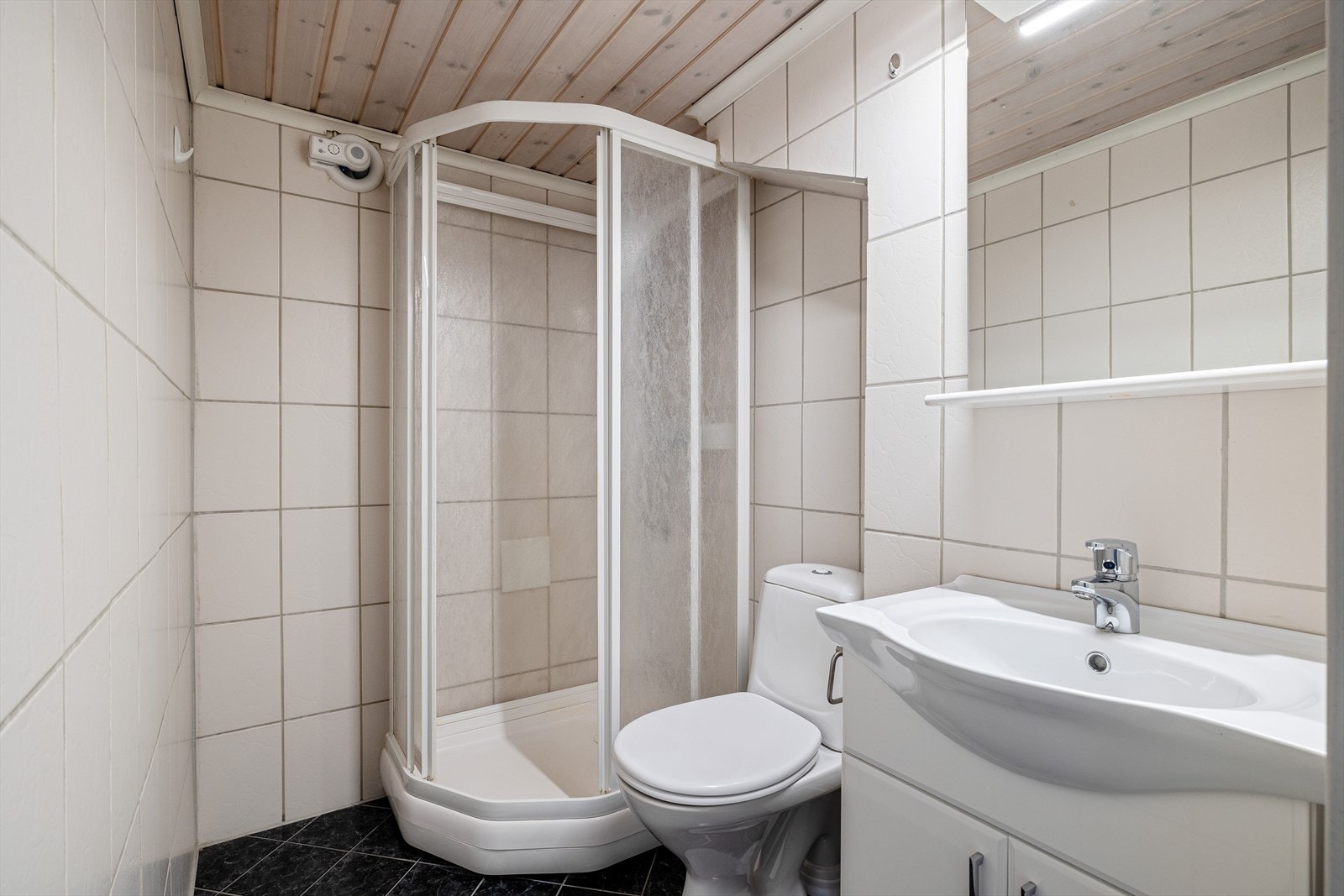 Pent baderom med flis på gulv og vegger. Innredet med kabinett, møbel m/servant, speil m/hylle og klosett. Galleribilde