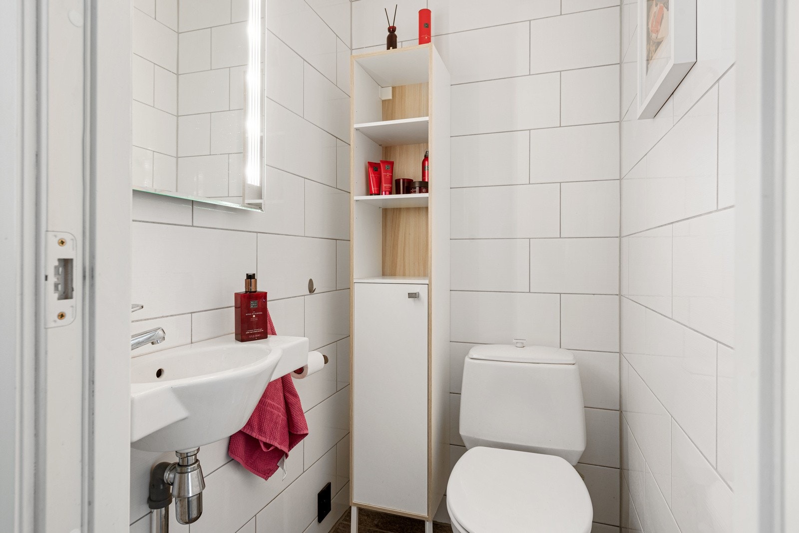 Wc-rommet er helfliset, utstyrt med toalett og gulvvarme. I rommet er det et delvis åpent høyskap, en enkel servant og et speil med integrert belysning. Galleribilde