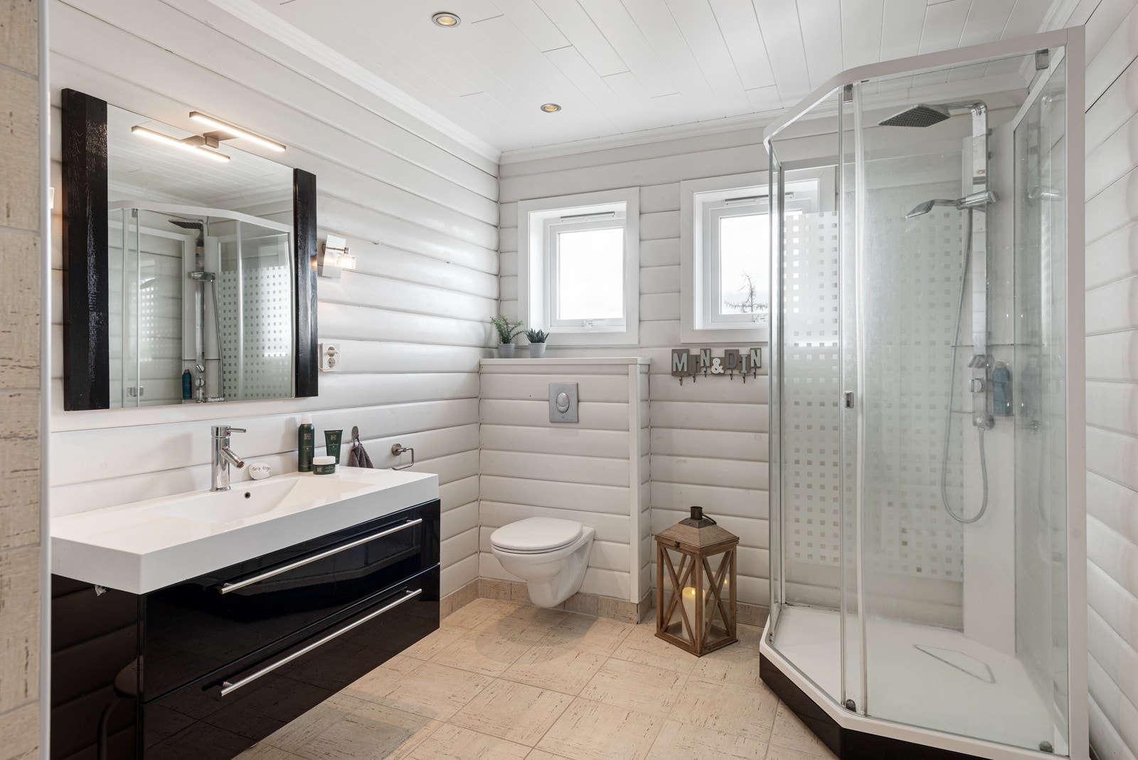 Badet har god størrelse, innredet med lyse gulvfliser og hvitmalte panelvegger. Galleribilde