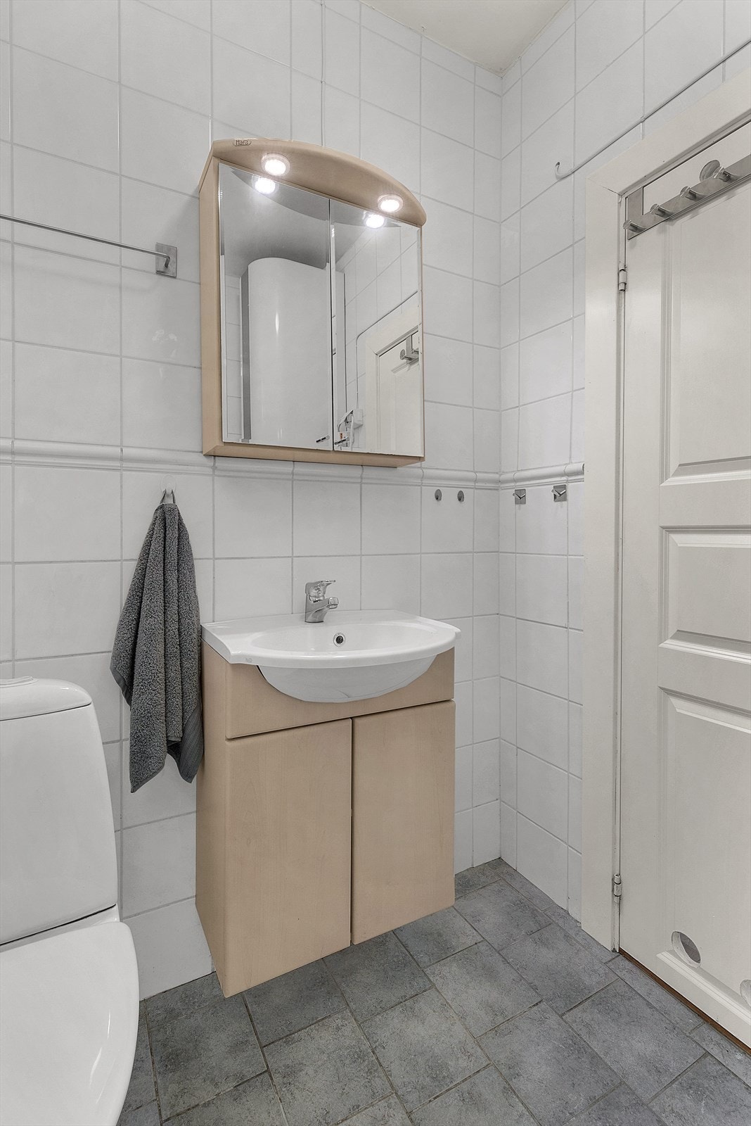 Flislagt bad med praktisk baderomsinnredning, toalett og opplegg for vaskemaskin. Galleribilde