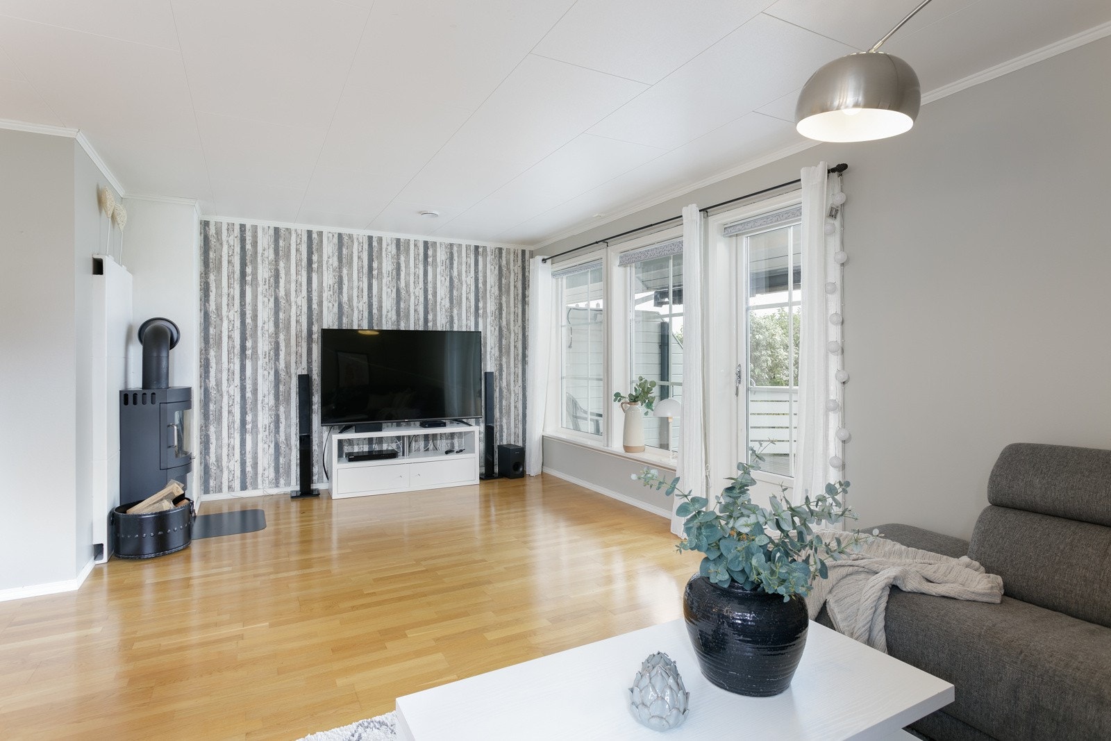 Stue fremstår som luftig med lyse overflater samt, store vinduer og dør ut mot terrasse Galleribilde