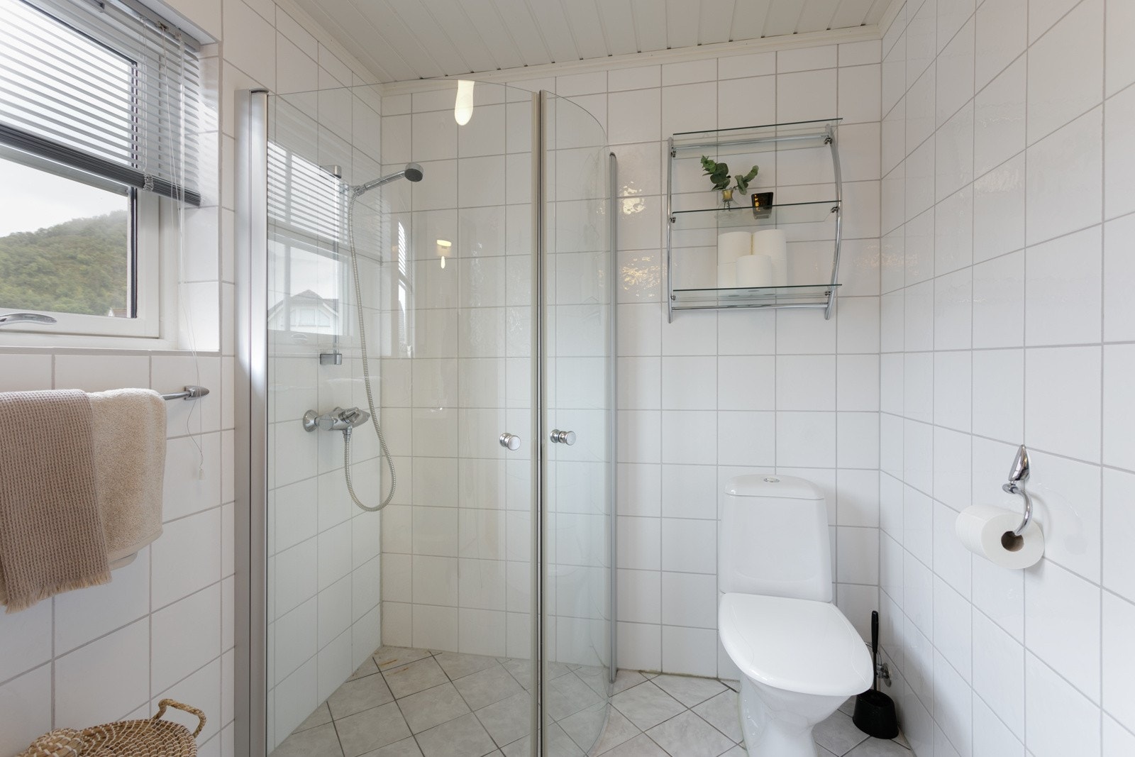 Badet har dusjhjørne med foldedører og gulvmontert toalett Galleribilde