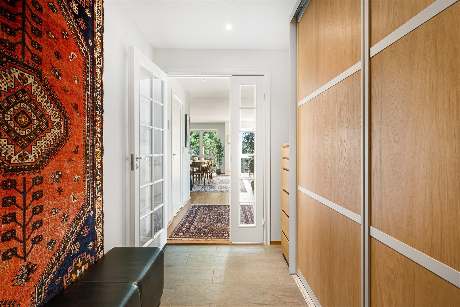 Lys og stilren entré med fliselagt gulv og downlights i himling, som gir et godt førsteinntrykk av leiligheten. Her er det god plass til å henge fra seg ytterklær og sette fra seg sko i stor skyvedørsgarderobe. Galleribilde